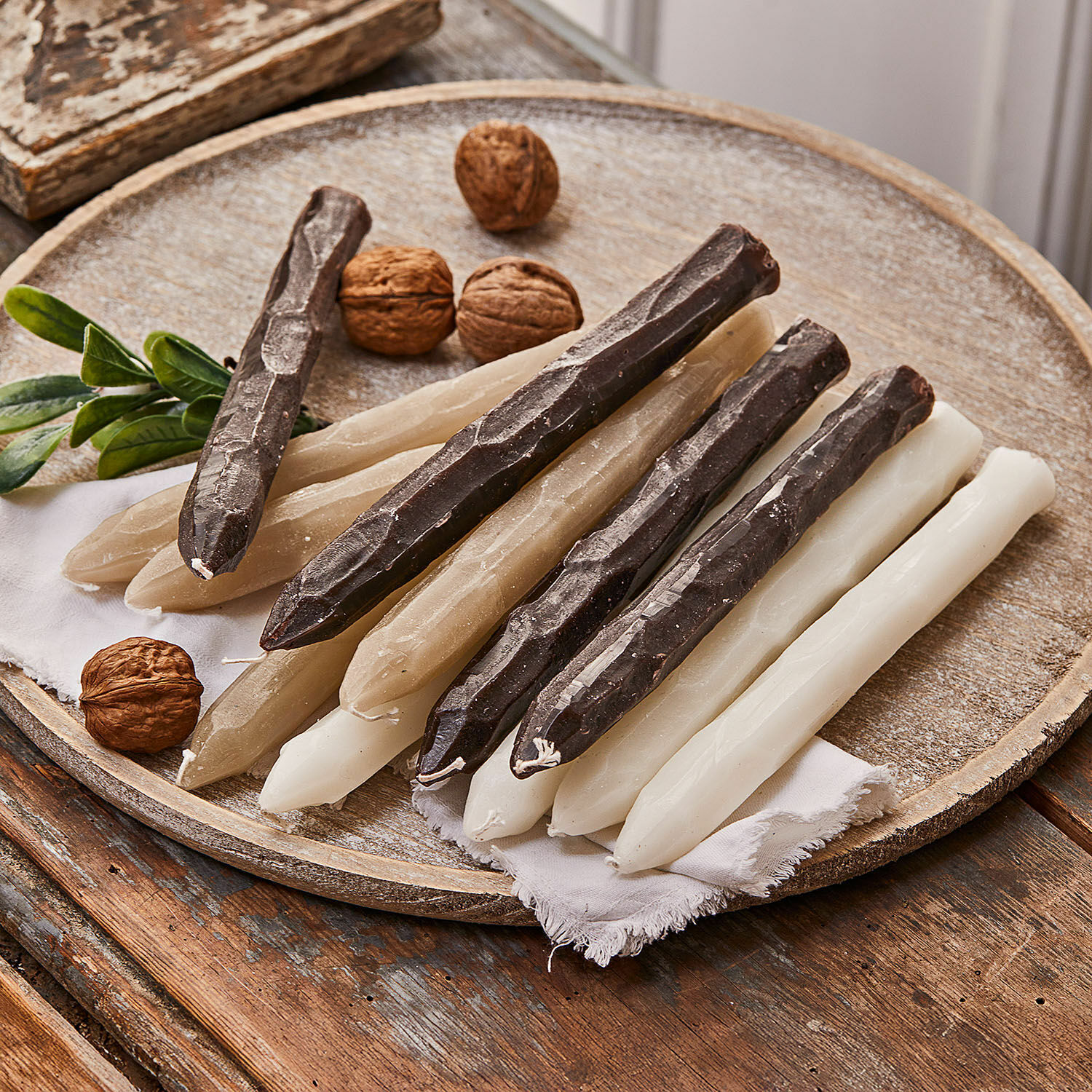 Set de 12 velas Savineau Conjunto de velas de mesa en blanco, beige y marrón sobre bandeja de madera con nueces decorativas