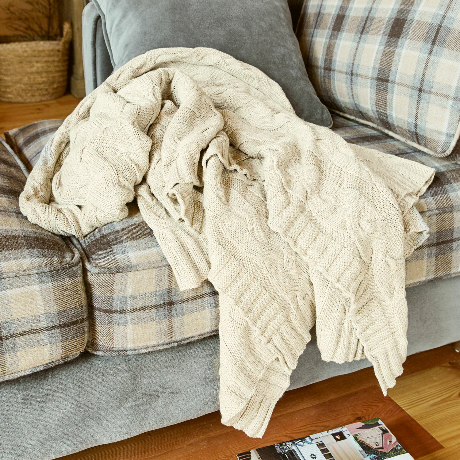 Plaid Arnhem Manta beige de algodón tejido sobre sofá gris con cuadros beige en sala de estar