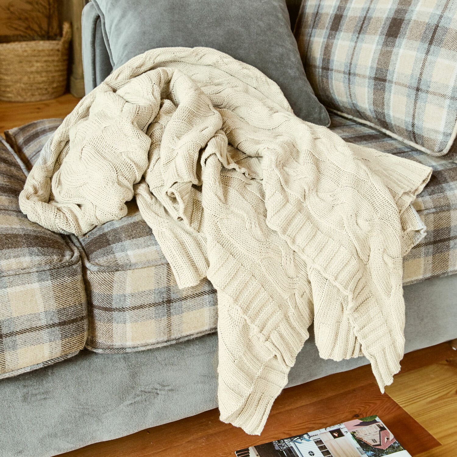 Plaid Arnhem Manta beige de algodón tejido sobre sofá gris con cuadros beige en sala de estar