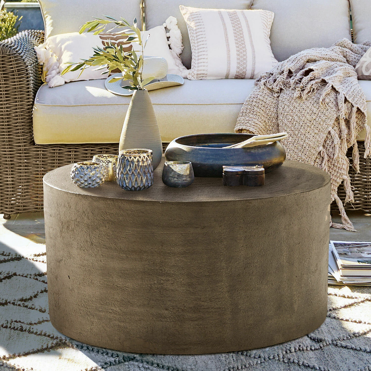 Mesa de centro Lexy Mesa de centro redonda de hormigón gris en terraza con decoraciones y sofá de ratán