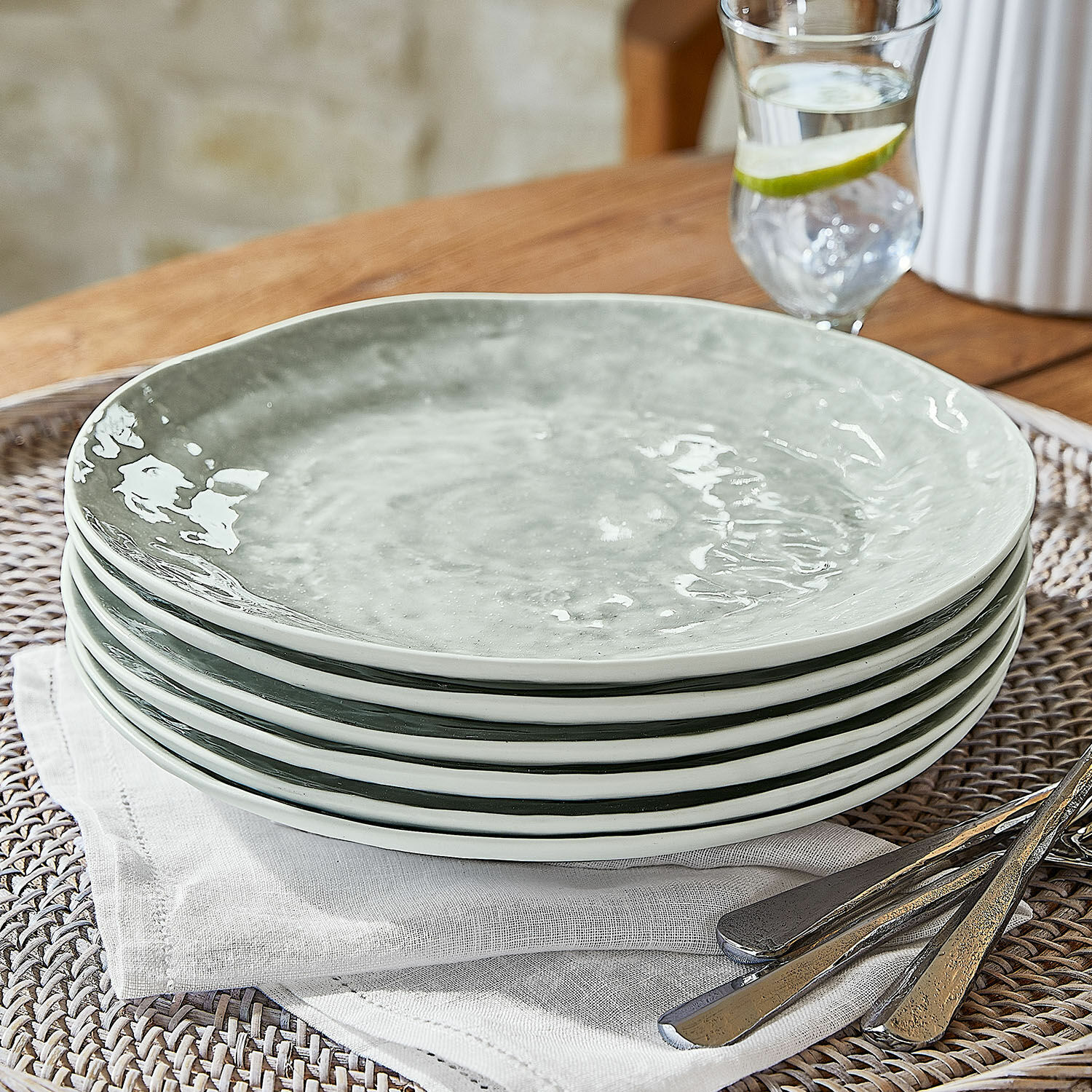 Set de 6 platos Braganza Conjunto de seis platos de cerámica gris sobre servilleta de lino con cubiertos metálicos