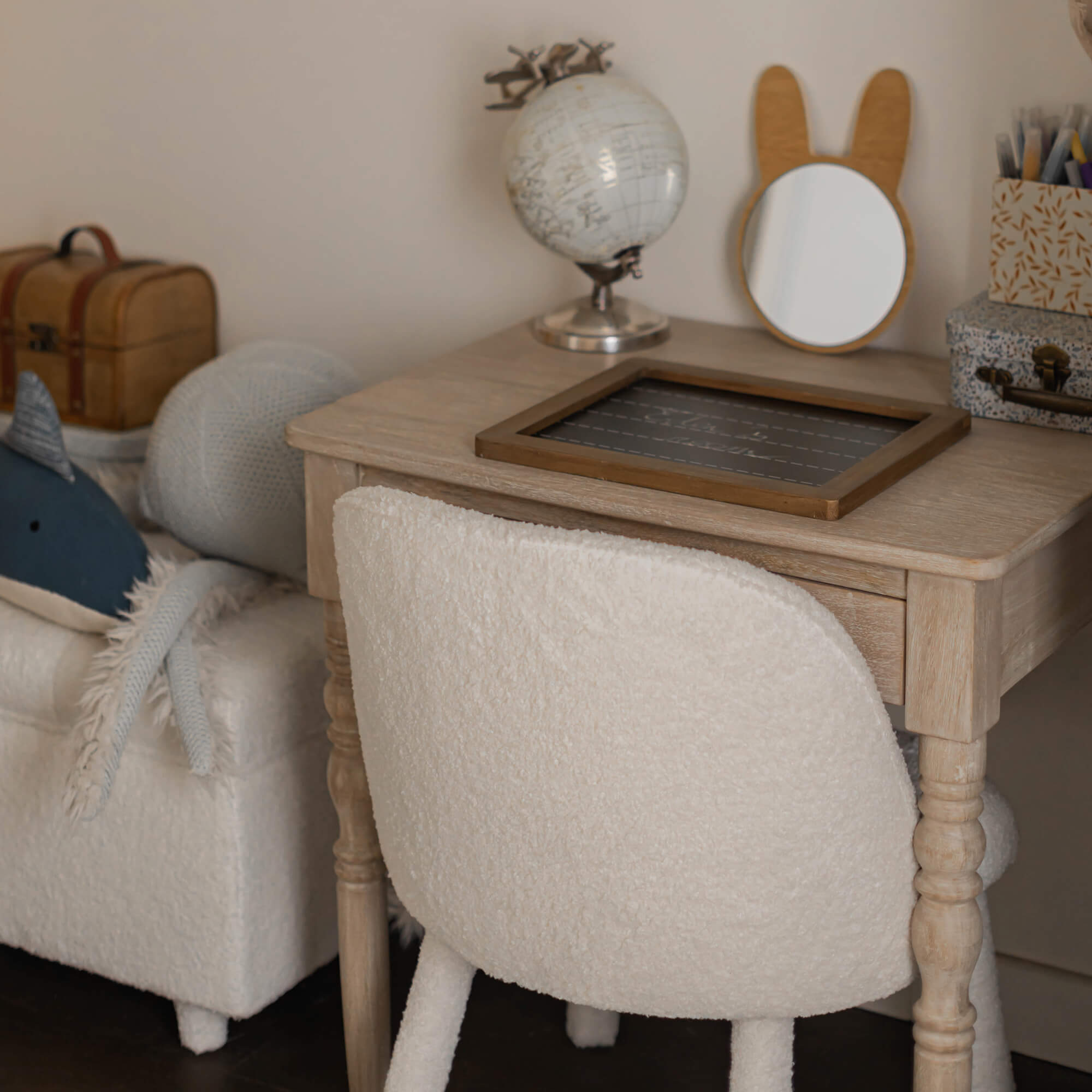 Escritorio de madera clara con silla beige de tela suave en habitación infantil acogedora