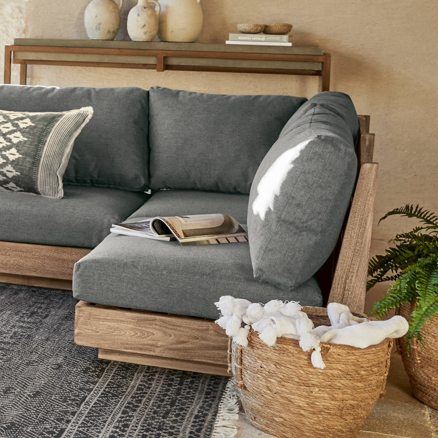 Sofaelement Courtelevant Sofá gris con estructura de madera y cojines suaves en sala moderna con cesta de mimbre