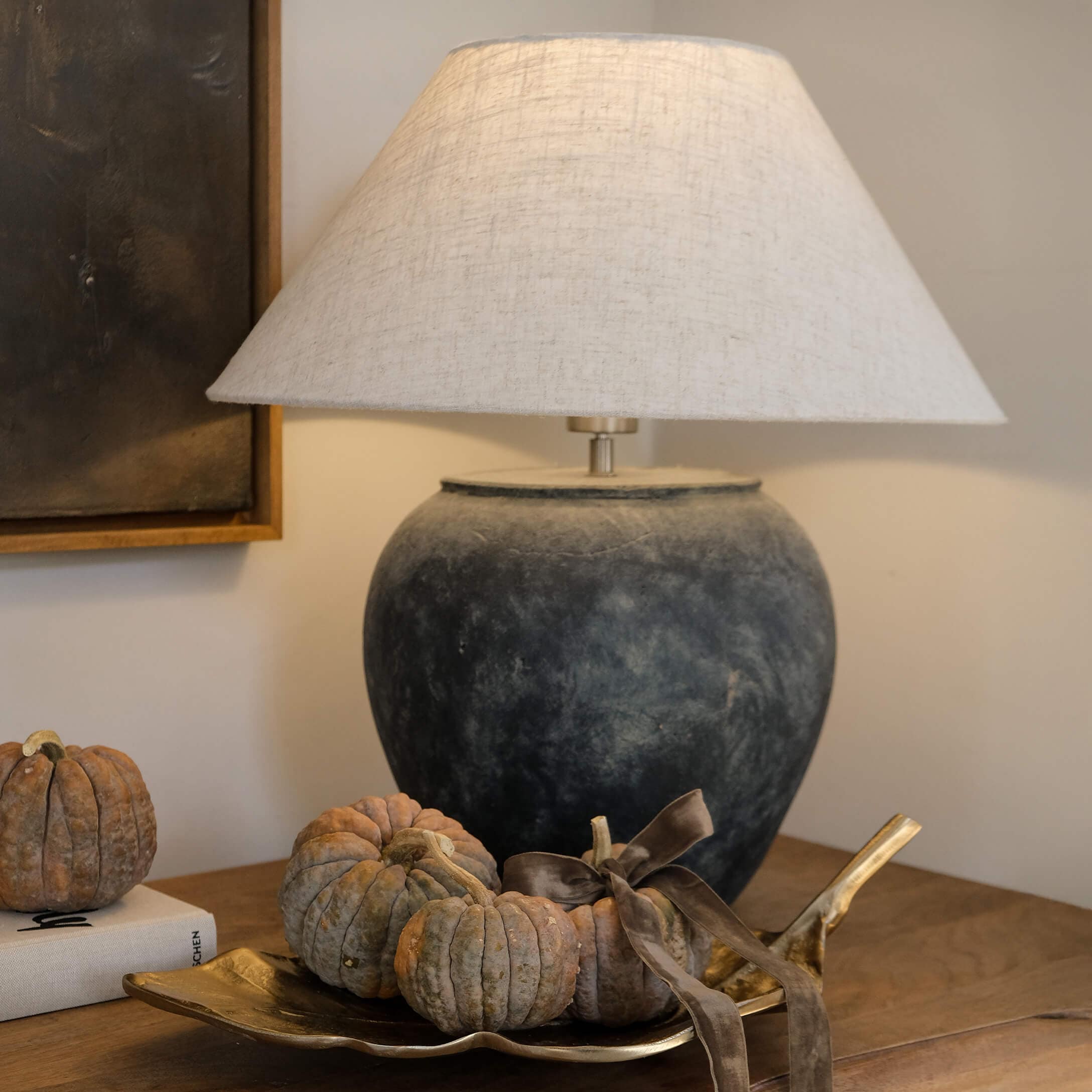 Lámpara de mesa de cerámica gris oscuro con pantalla beige y decoración de pequeñas calabazas en bandeja dorada