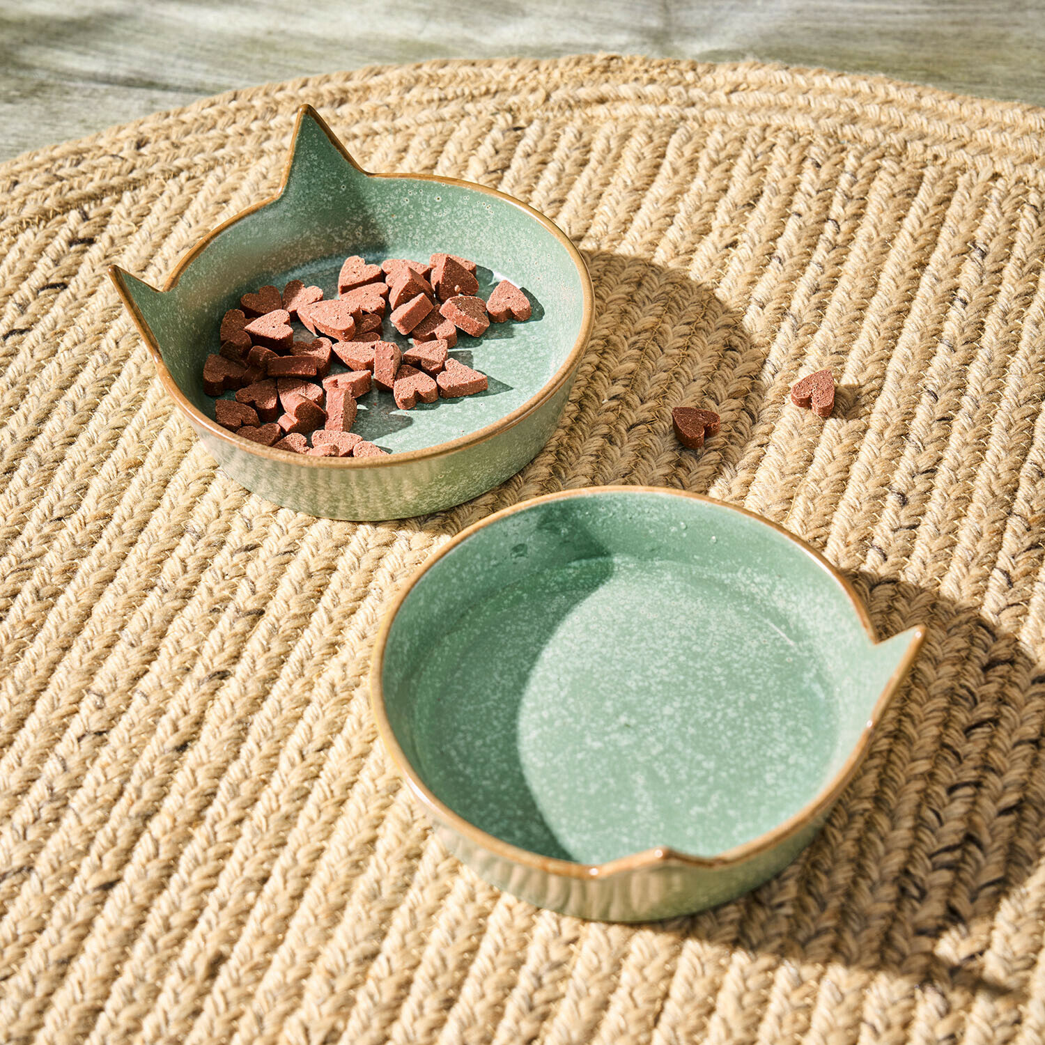 Cuenco de cerámica verde con orejas de gato sobre alfombra trenzada, cuenco con comida para gatos en forma de corazón