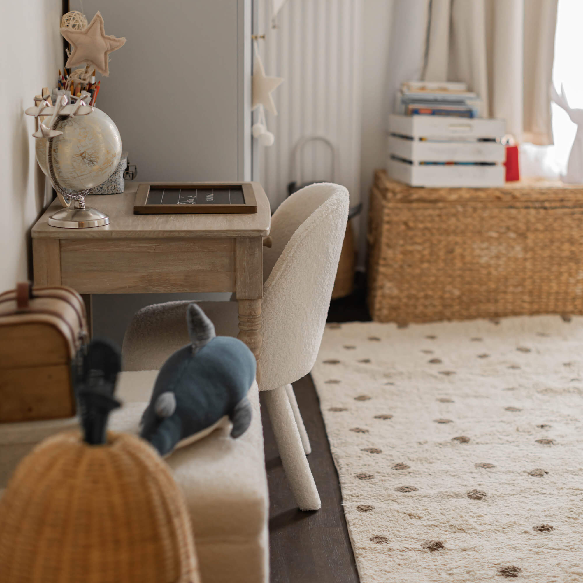 Silla blanca de material suave junto a escritorio de madera clara en habitación infantil acogedora