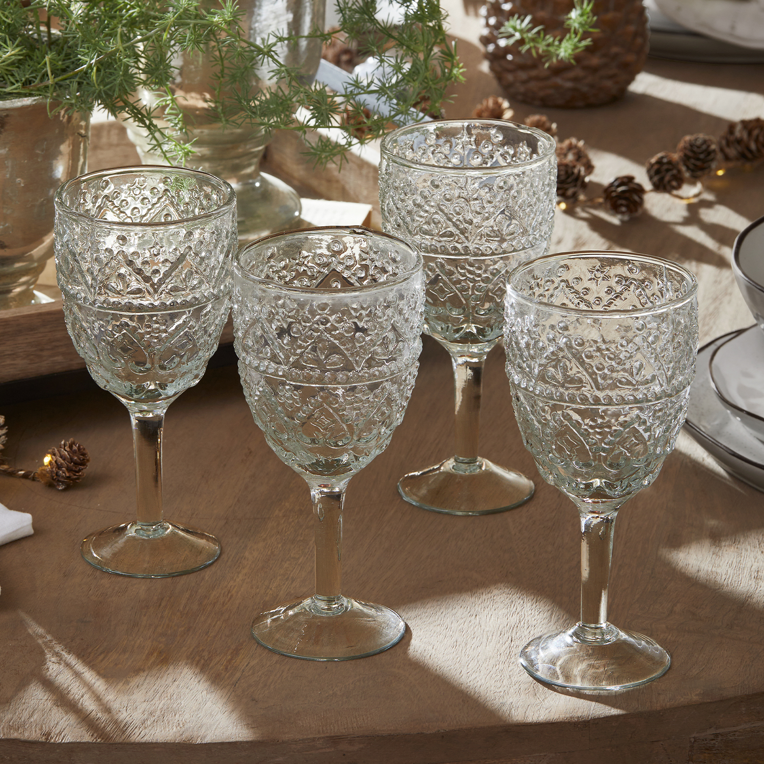 Conjunto de cuatro vasos transparentes con diseño decorativo sobre mesa de madera para servir bebidas