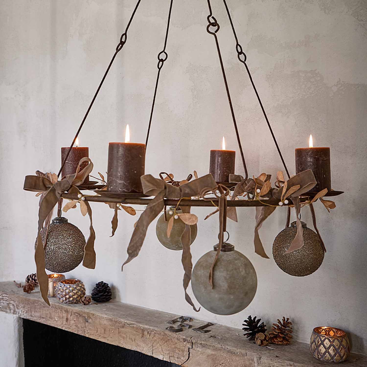 Candelabro colgante de metal con cuatro velas marrones y bolas decorativas en la pared