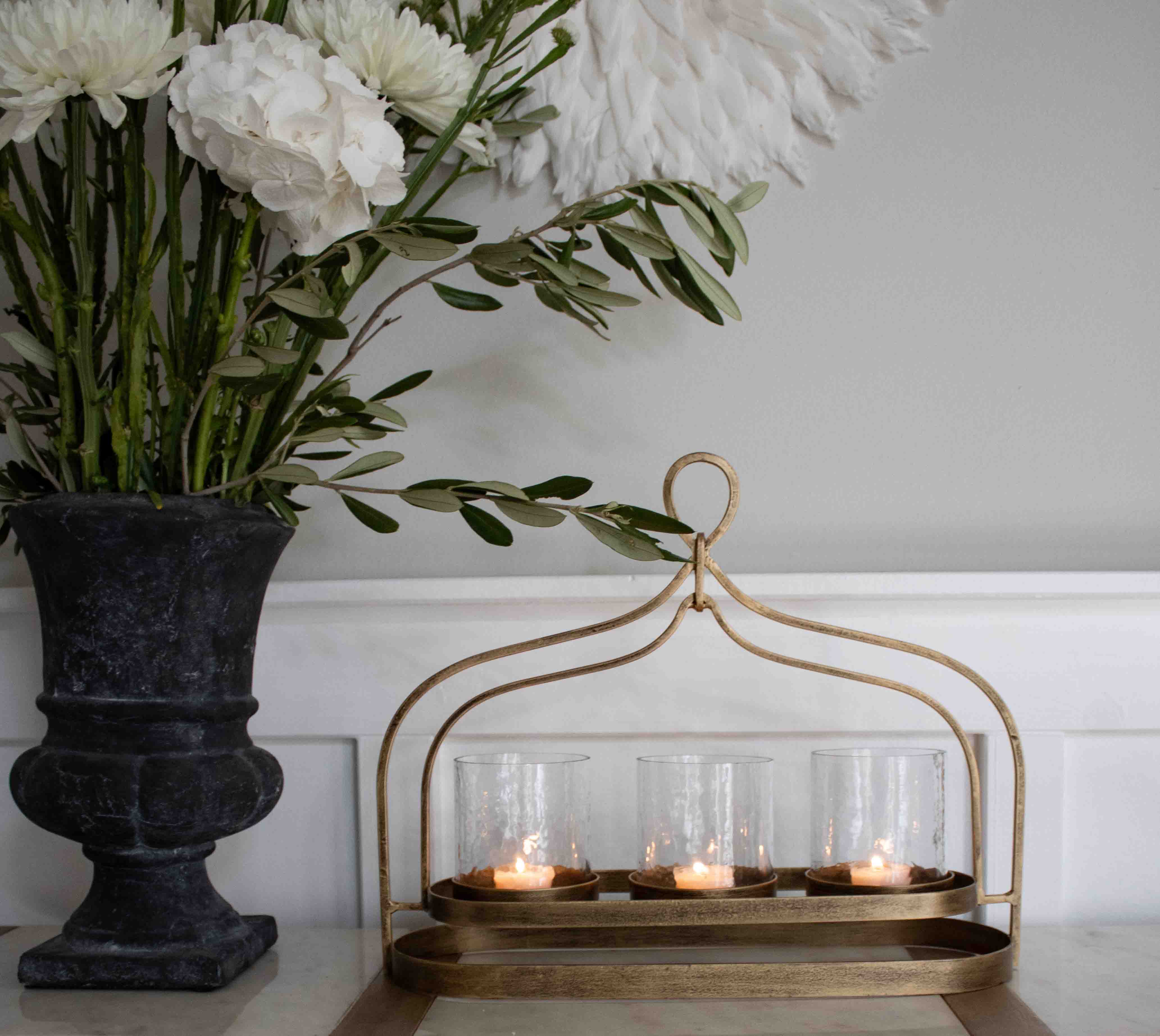 Portavelas metálico dorado con tres vasos de cristal para velas tealight sobre mesa decorativa