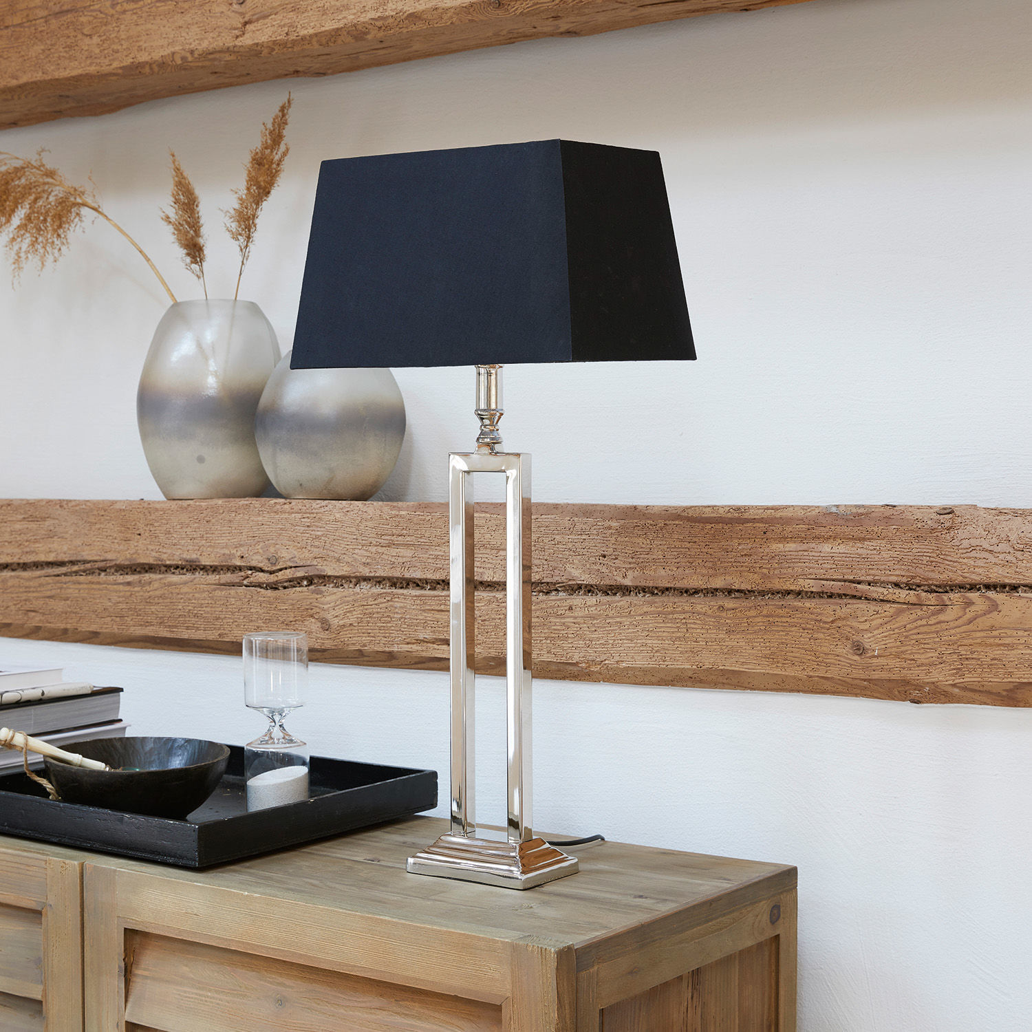 Lámpara de mesa Kinshaa Lámpara de mesa elegante con base metálica y pantalla negra sobre mueble de madera clara