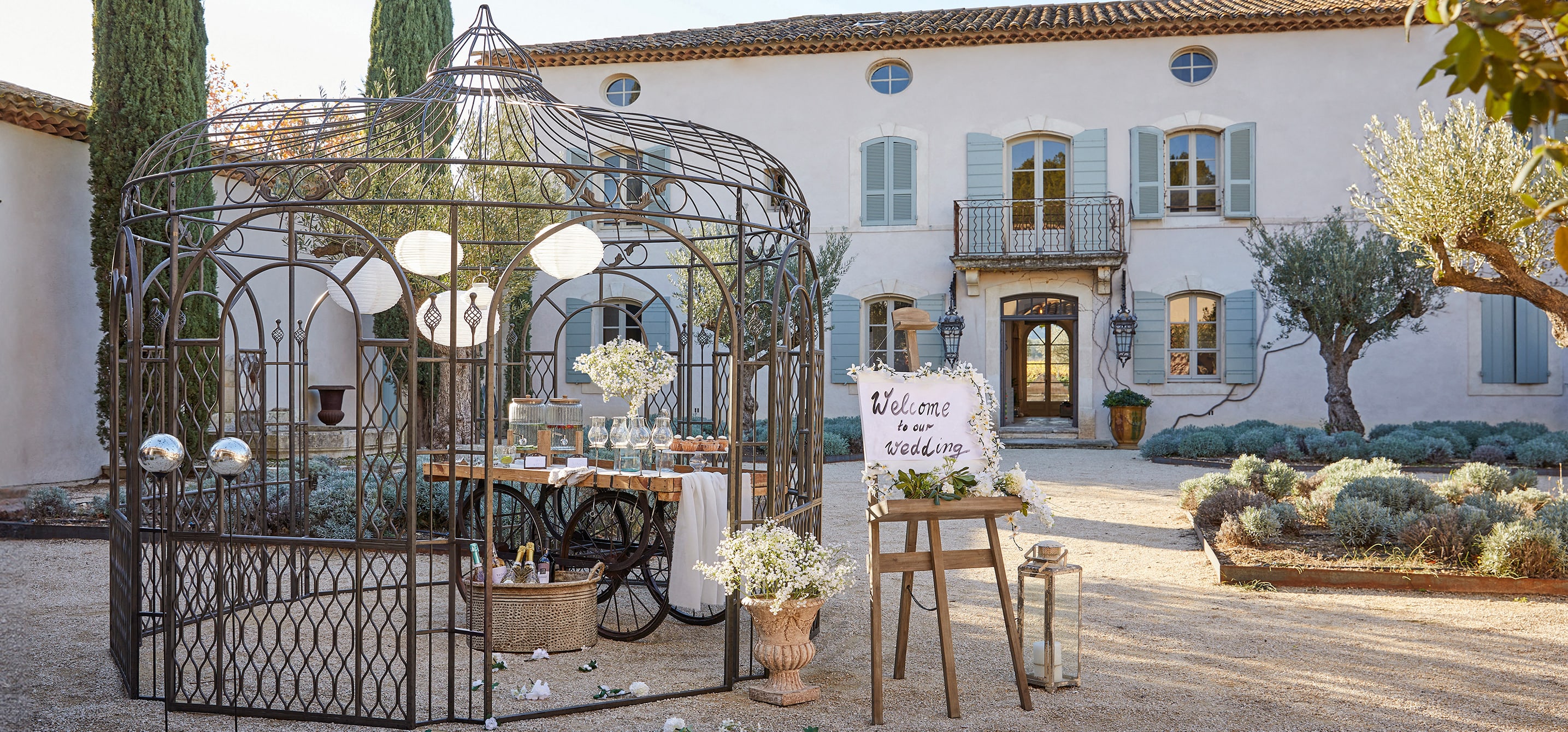 Pérgola de jardín de metal con diseño decorativo y faroles, preparada para una fiesta de boda al aire libre