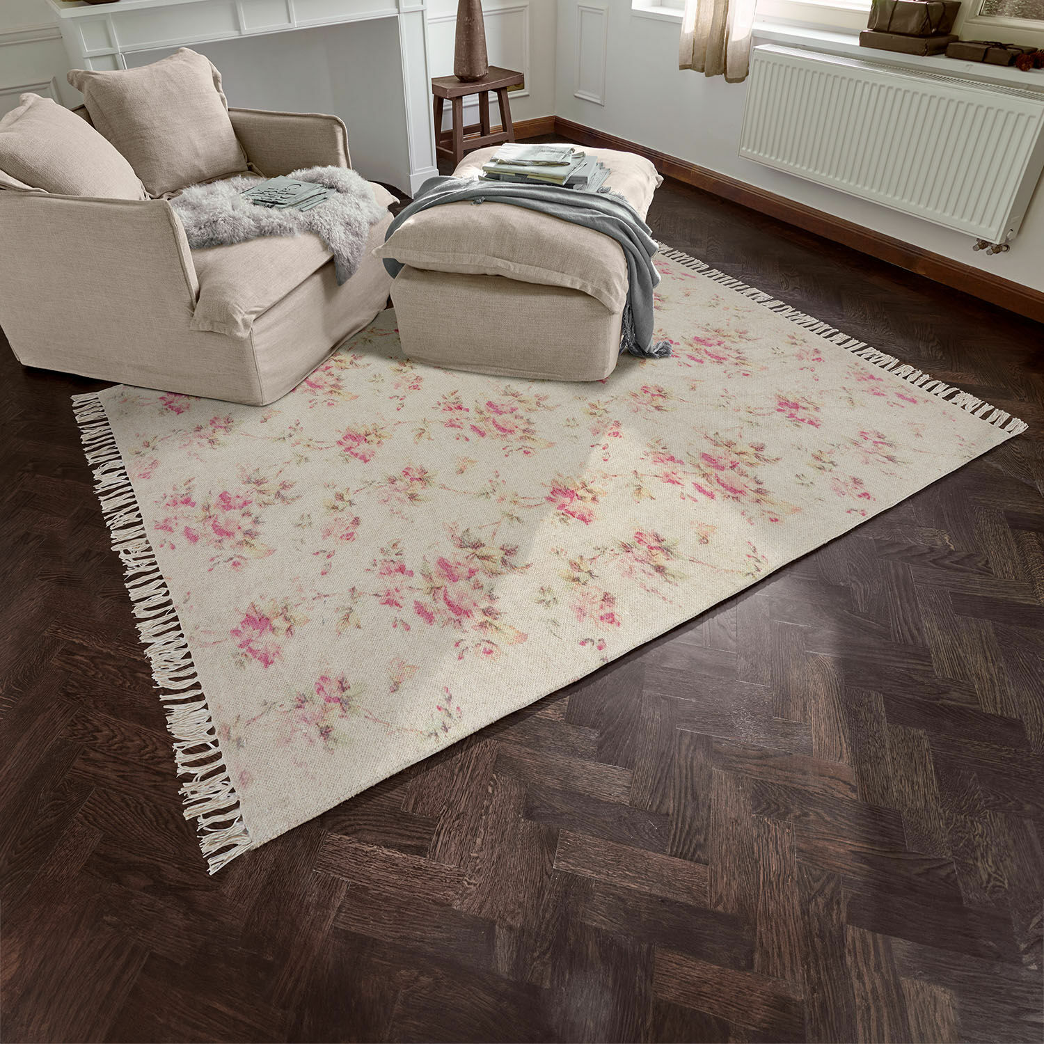 Alfombra beige con diseño floral y flecos sobre suelo de madera oscura en sala de estar