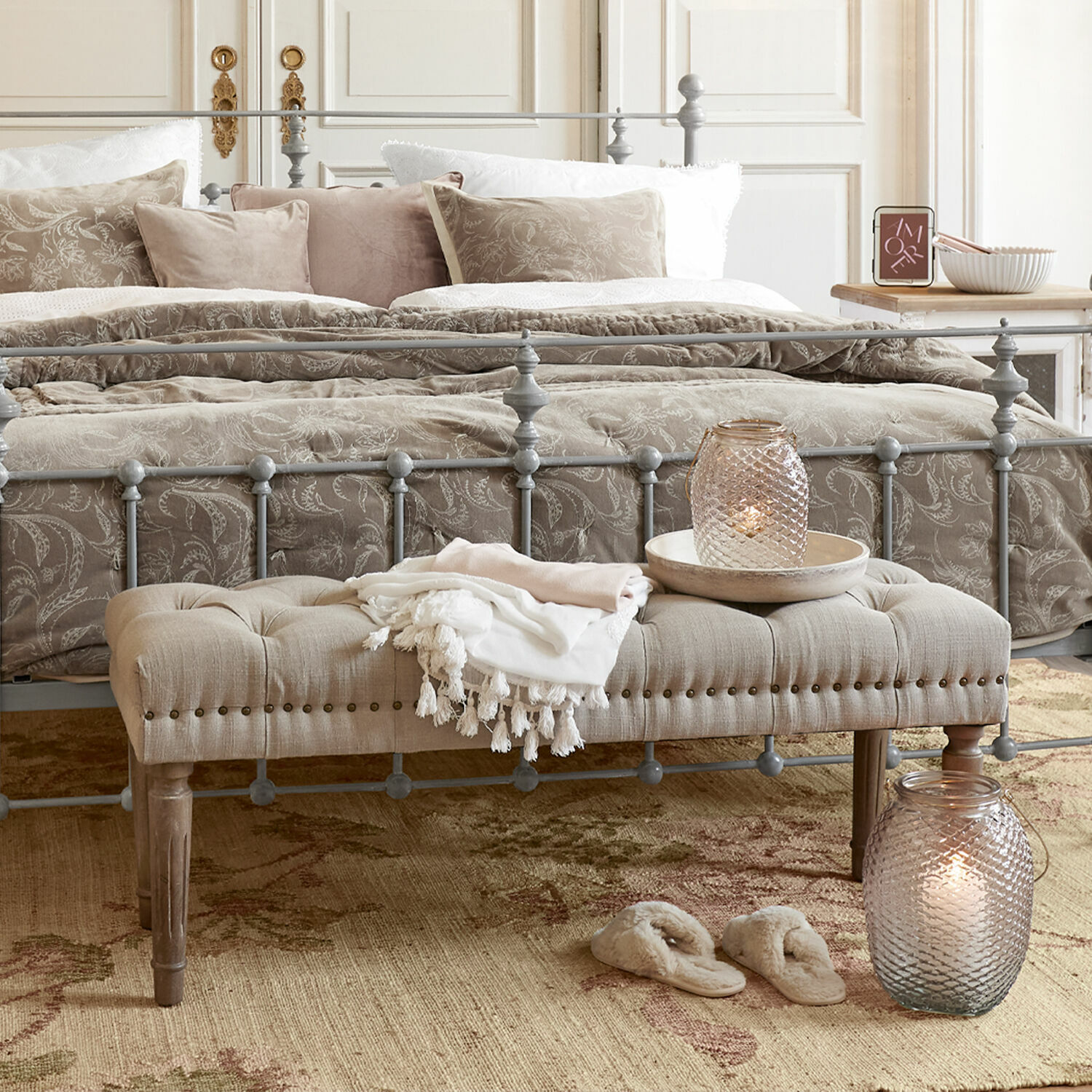 Banco Brookfield Cama de metal gris con banco beige acolchado y cojines decorativos en dormitorio acogedor