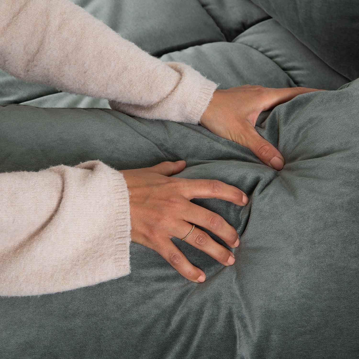 Manos tocando tapicería de terciopelo verde suave con capitoné, tela cómoda para muebles