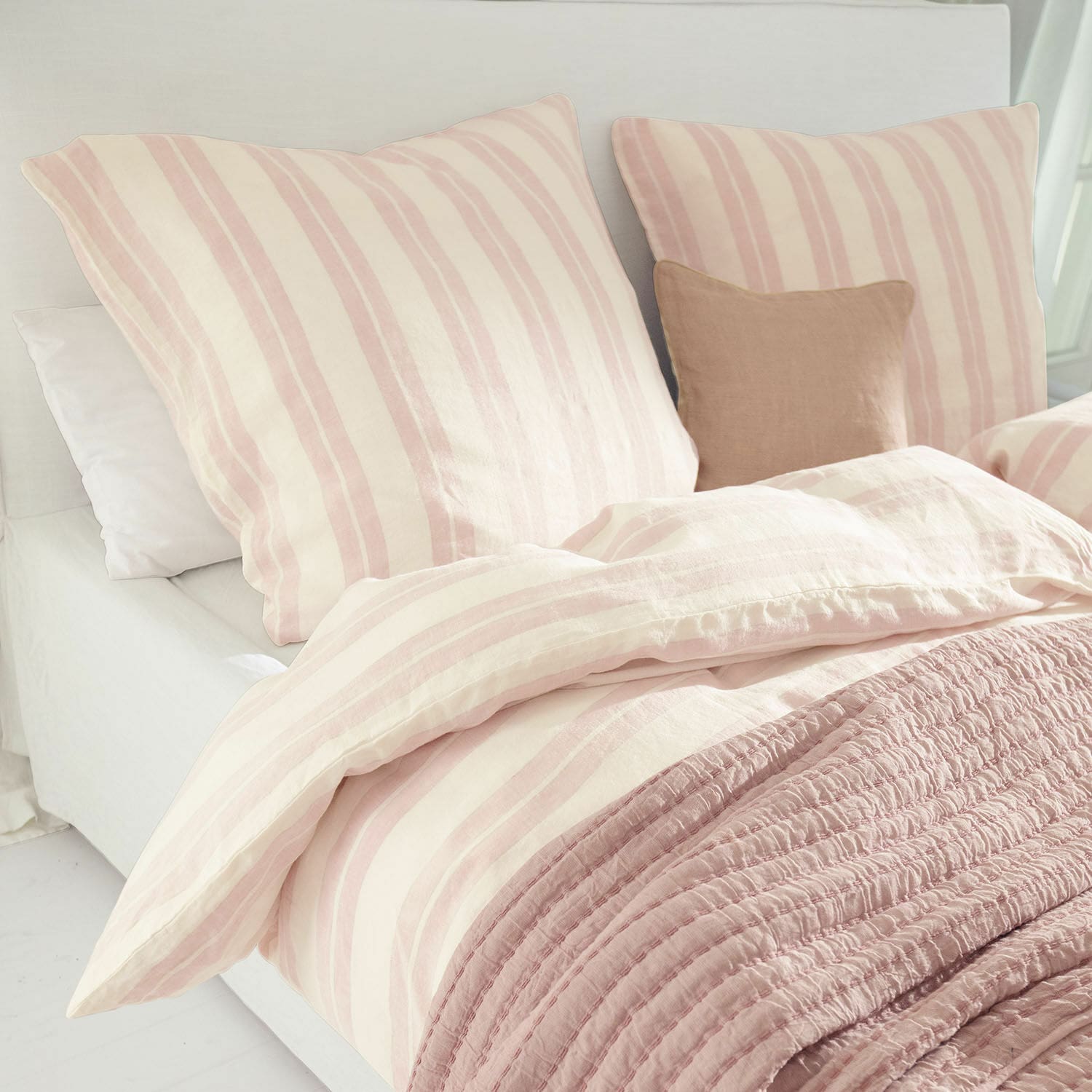 Ropa de cama Dordogne Ropa de cama de algodón con rayas rosa y crema y manta rosa suave sobre cama en habitación luminosa