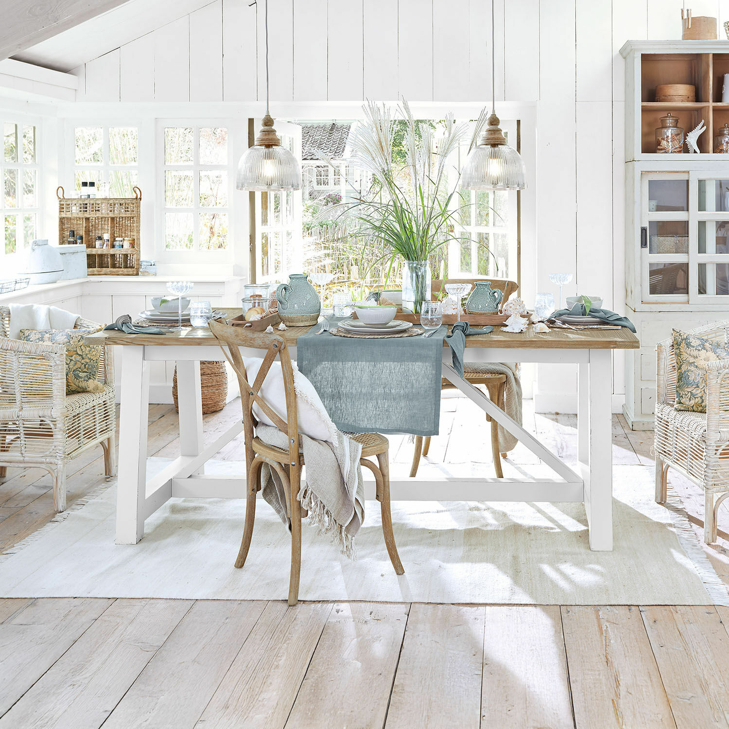 Mesa de comedor Dubberly Comedor rústico con mesa de madera, sillas de mimbre, decoración natural y luz natural