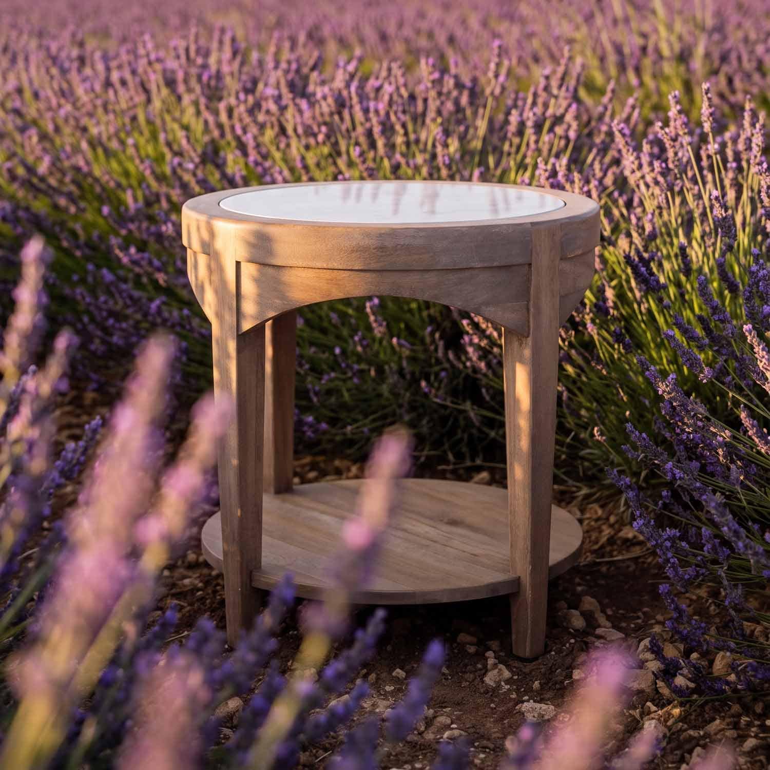 Mesa redonda de madera con superficie blanca, situada entre flores de lavanda moradas al aire libre