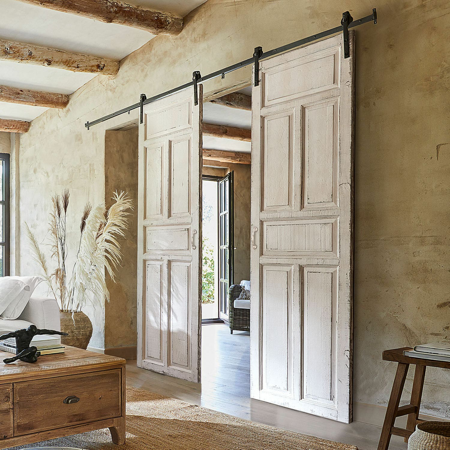Doble puerta corredera Mallothra Puertas correderas blancas de madera con sistema metálico en interior rústico con decoración natural