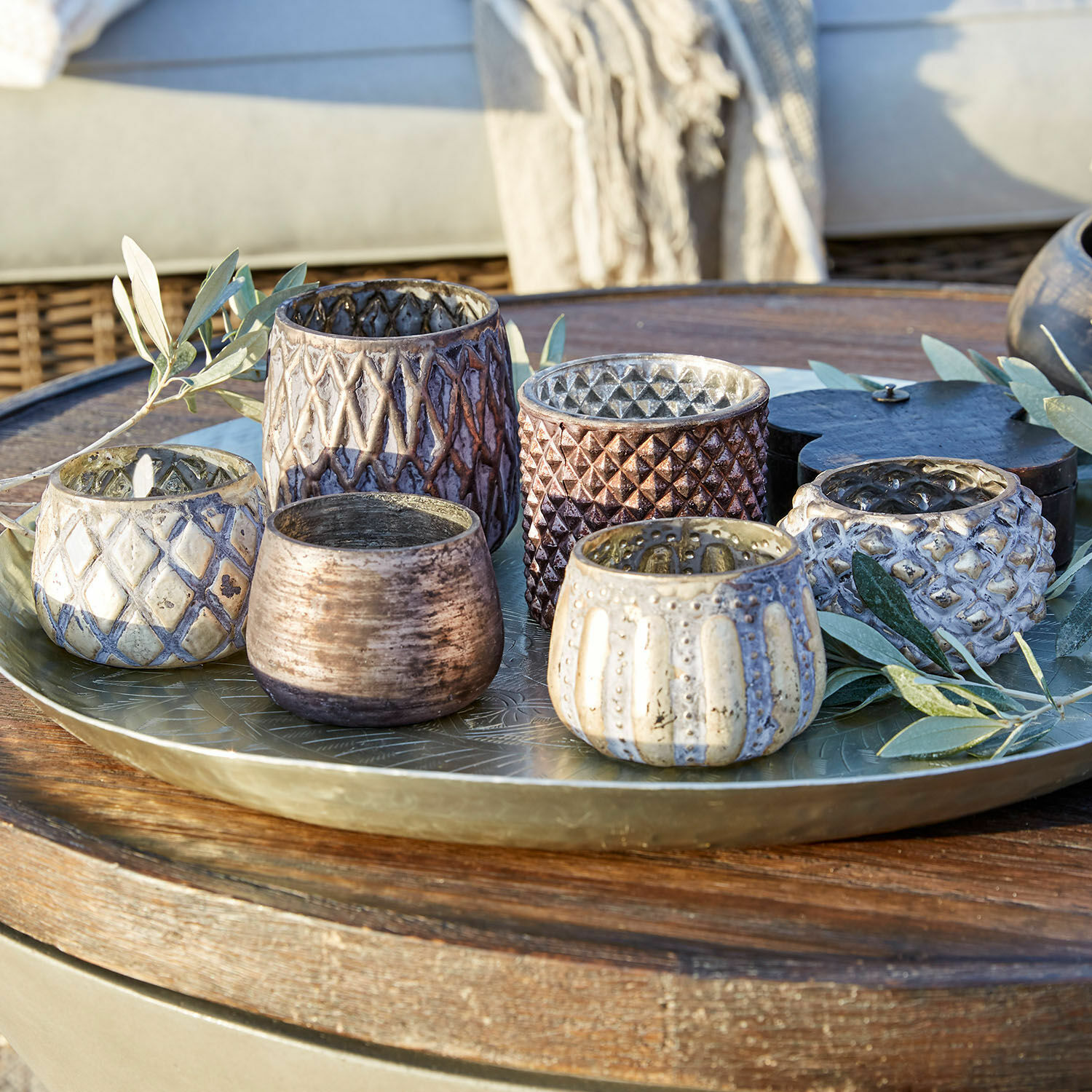 Conjunto de seis portavelas de cerámica en tonos marrones y beige sobre bandeja metálica decorativa