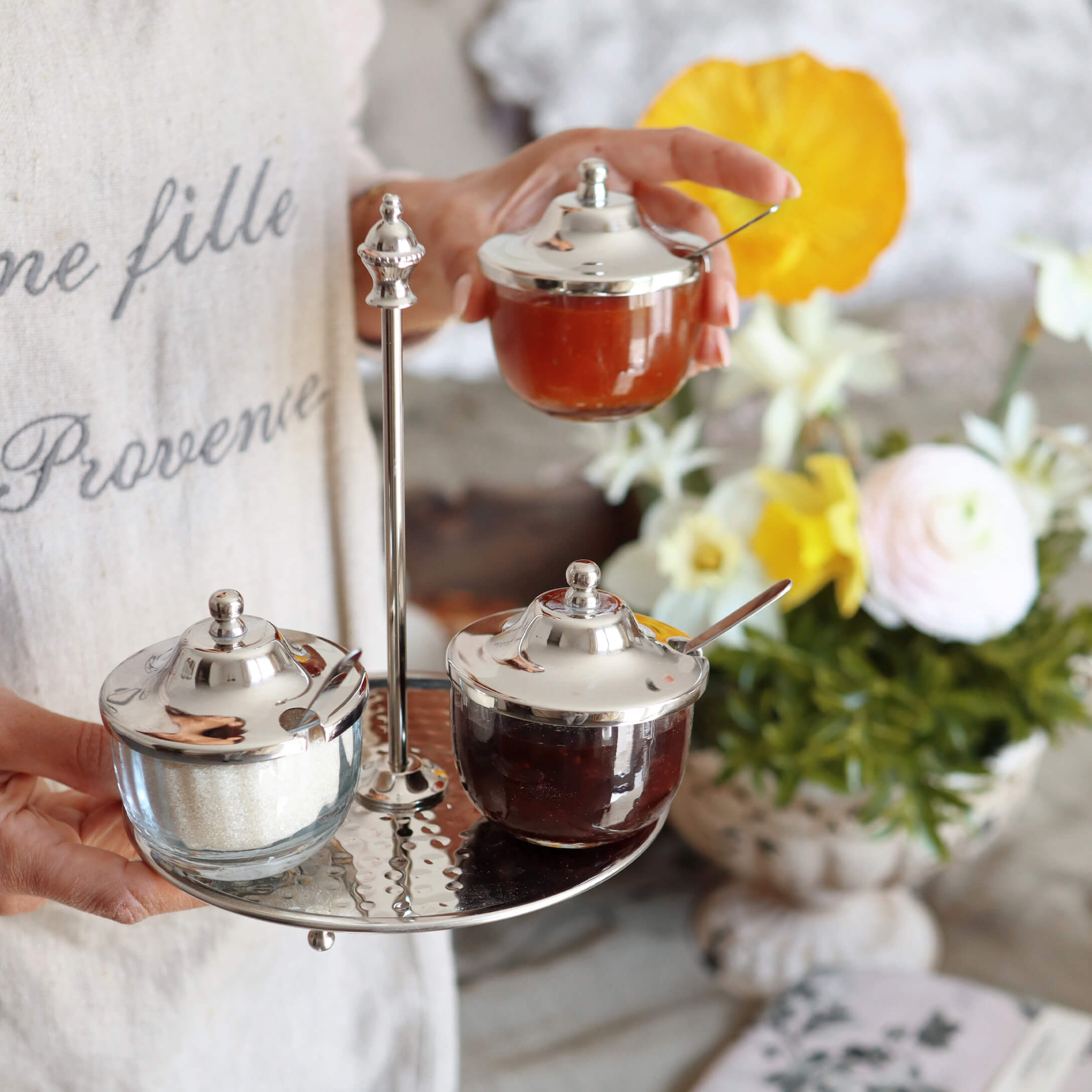 Recipientes de vidrio con tapas metálicas en bandeja metálica, con mermelada y azúcar