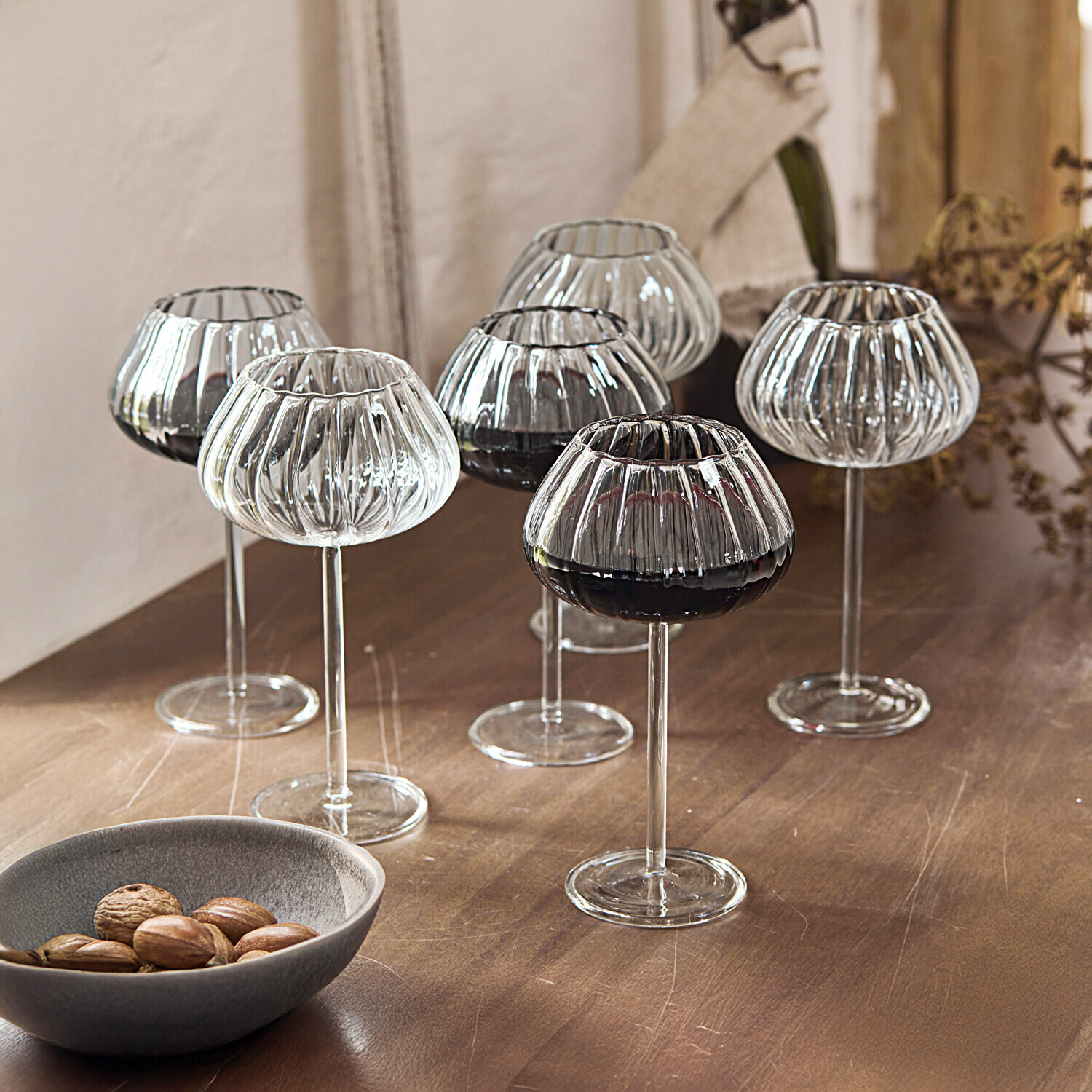 Set de 6 copas de vino Minou Conjunto de seis copas de vino transparentes de vidrio estriado con tallo largo sobre mesa de madera