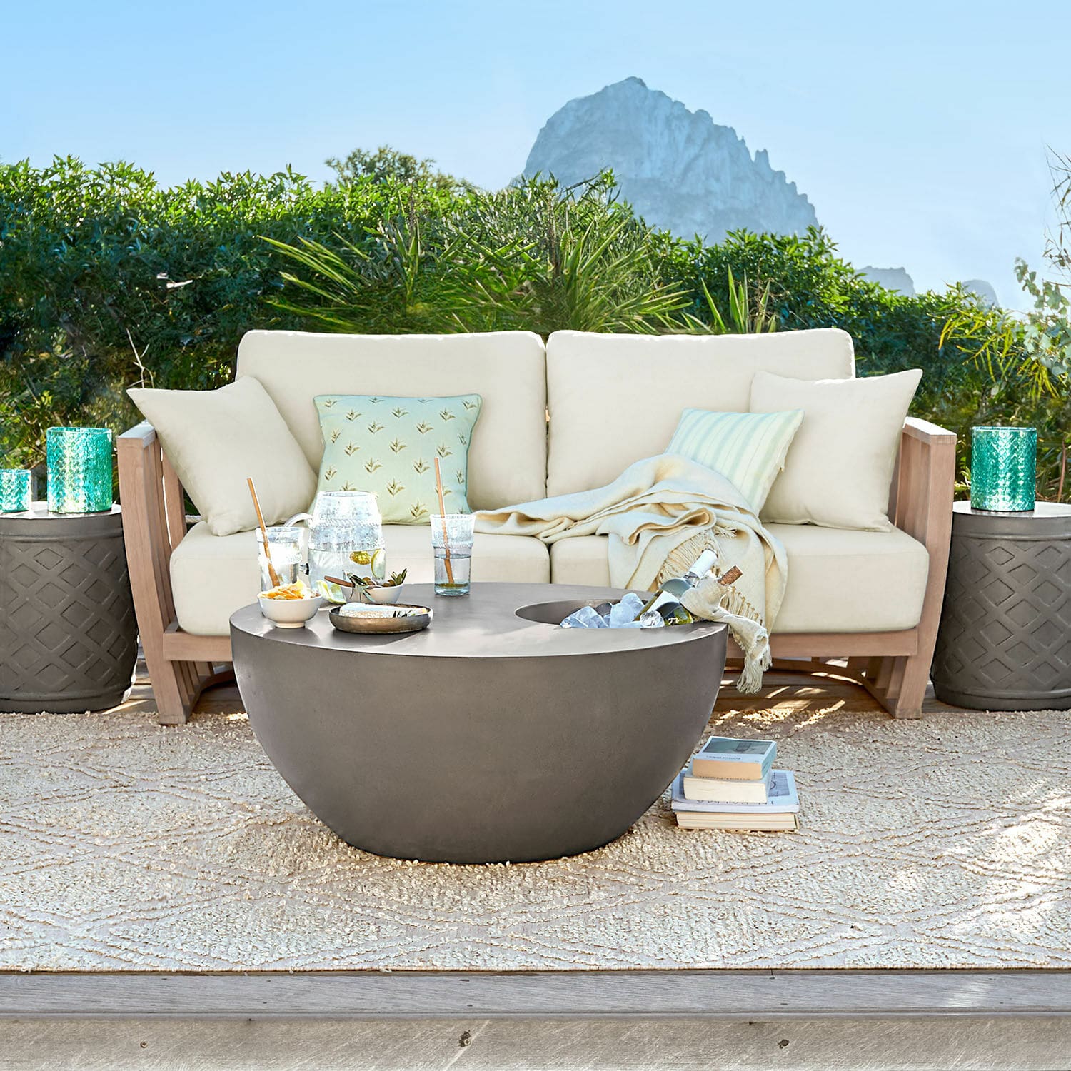 Sofá FSC®-100% Vézère Mesa de jardín redonda moderna de hormigón gris en terraza con sofá beige y cojines