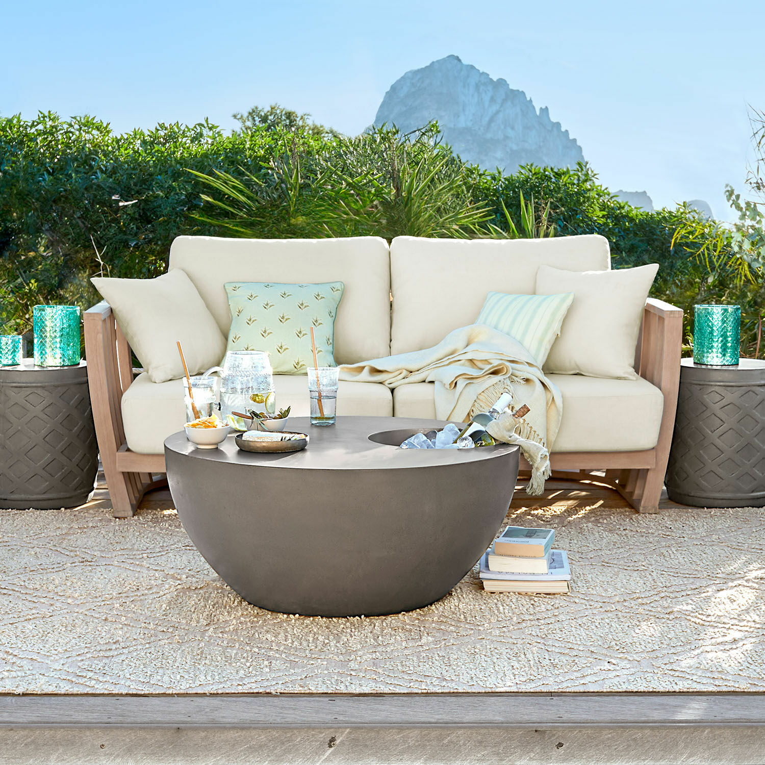 Sofá FSC®-100% Vézère Mesa de jardín redonda moderna de hormigón gris en terraza con sofá beige y cojines