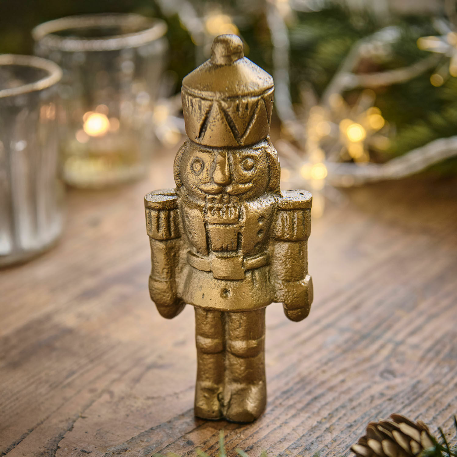 Figura decorativa Zarilith Figura de cascanueces metálica dorada sobre mesa de madera, decoración navideña