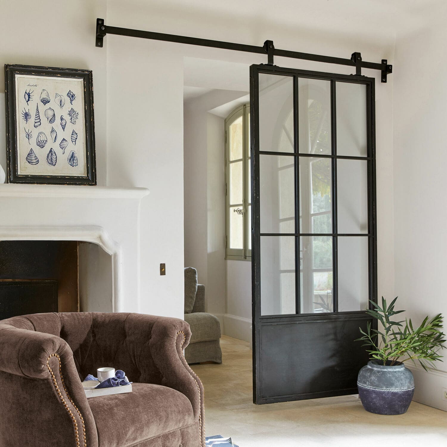 Puerta corredera Luisant Puerta corredera estilo loft de metal negro y vidrio en interior moderno con sillón y chimenea