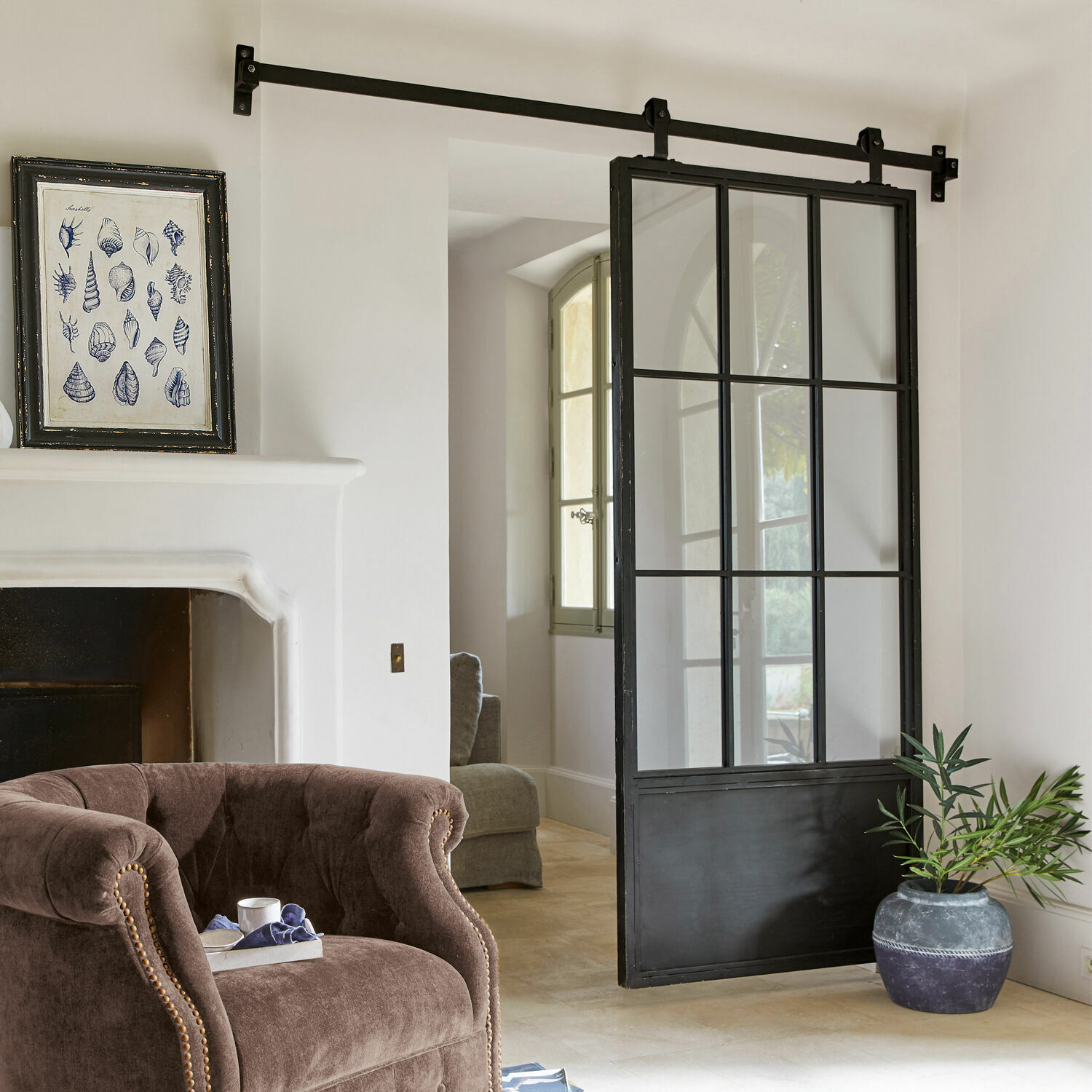 Puerta corredera Luisant Puerta corredera estilo loft de metal negro y vidrio en interior moderno con sillón y chimenea