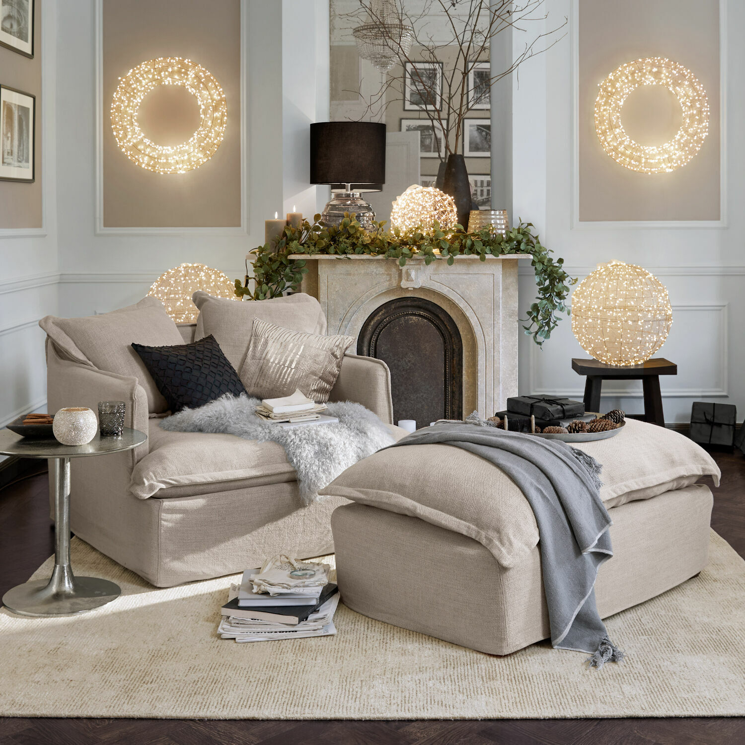 Sillón y reposapiés beige de tela en sala acogedora con luces decorativas y chimenea