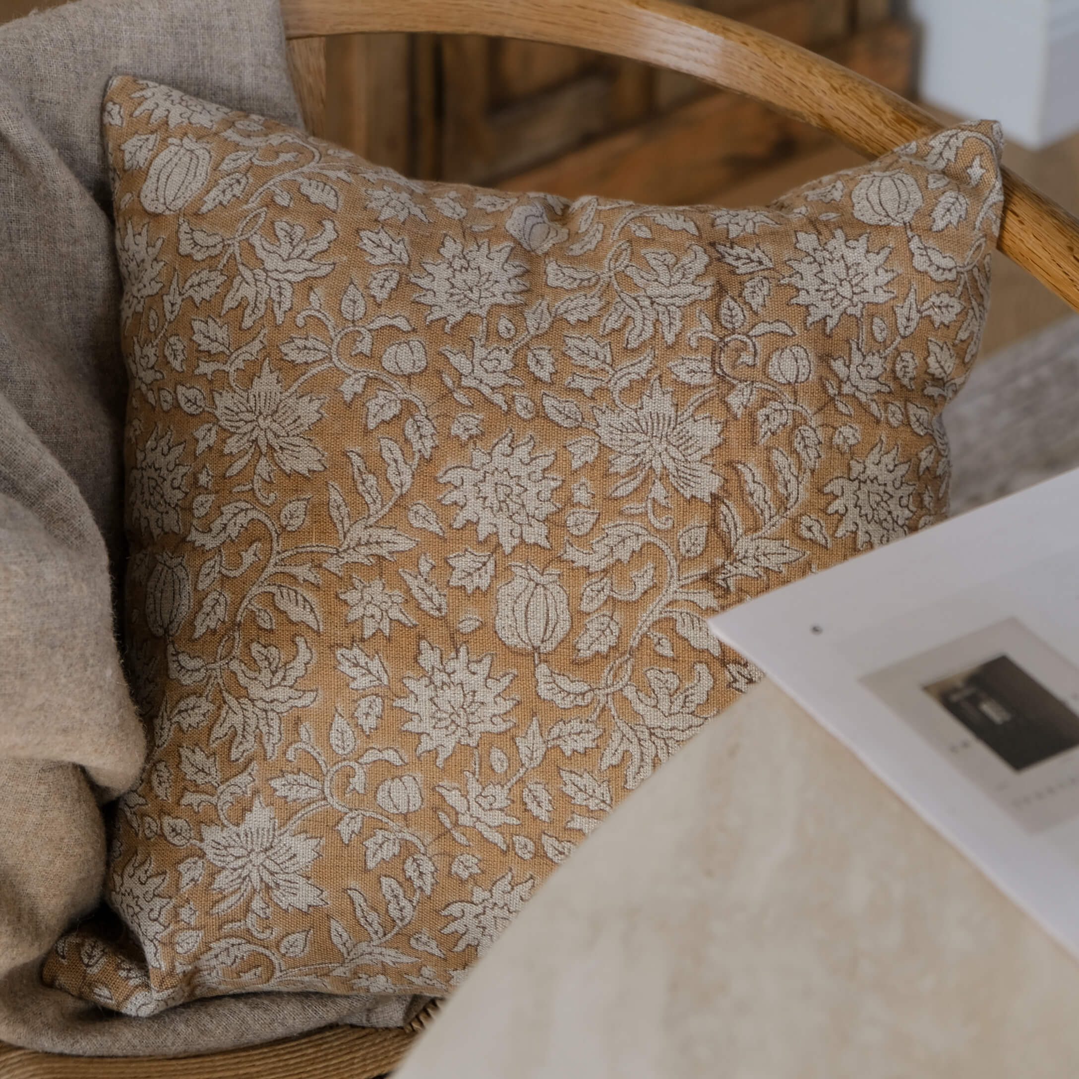 Cojín decorativo de algodón beige con diseño floral blanco para sala de estar acogedora