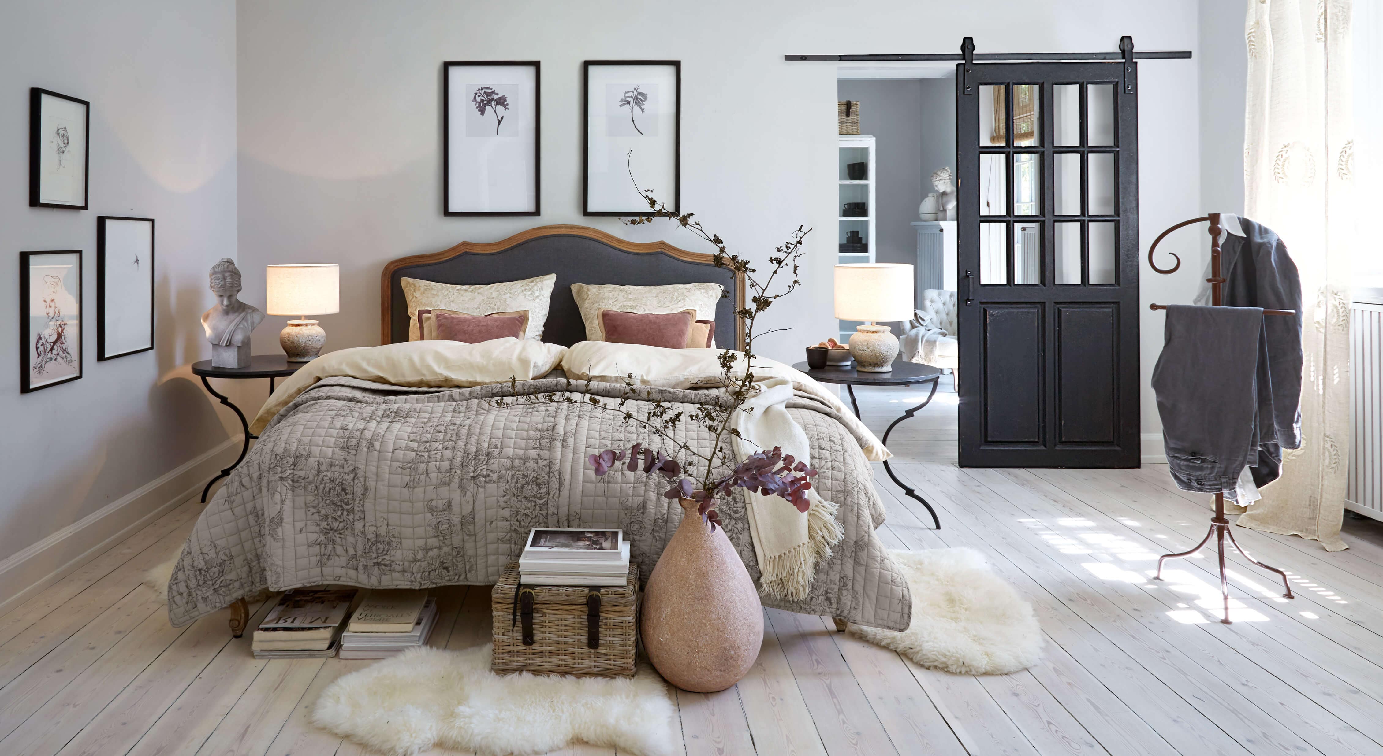 Dormitorio acogedor con cama en ropa de cama gris-beige y mesitas negras con lámparas