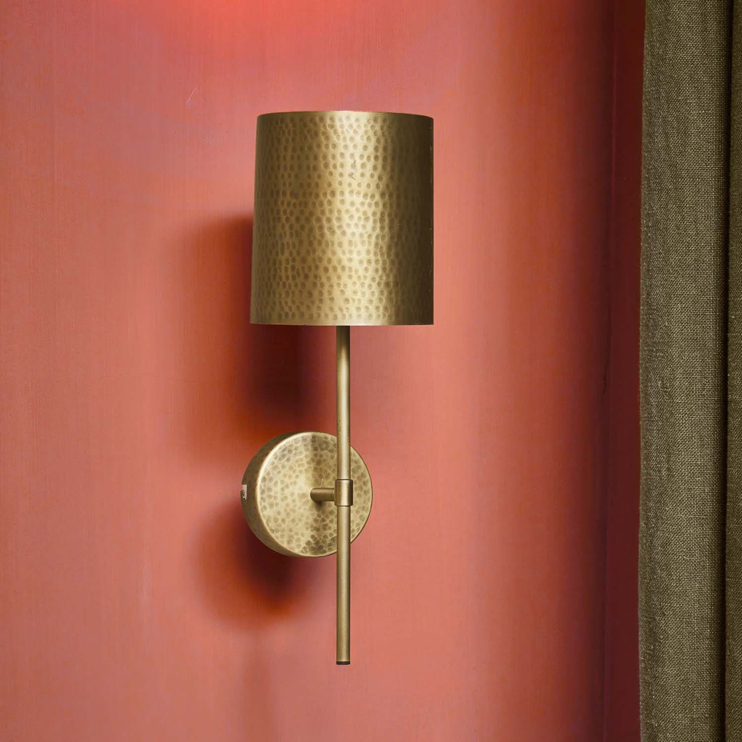 Aplique de pared de latón martelé con pantalla cilíndrica en pared roja, luz decorativa