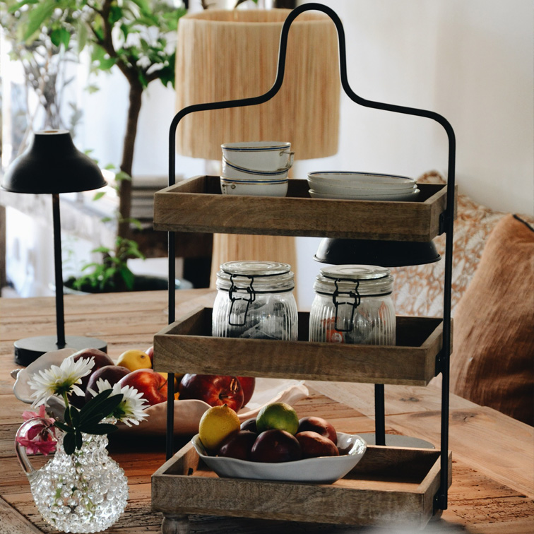 Estantería de tres niveles de madera y metal con vajilla y frutas sobre mesa rústica en comedor