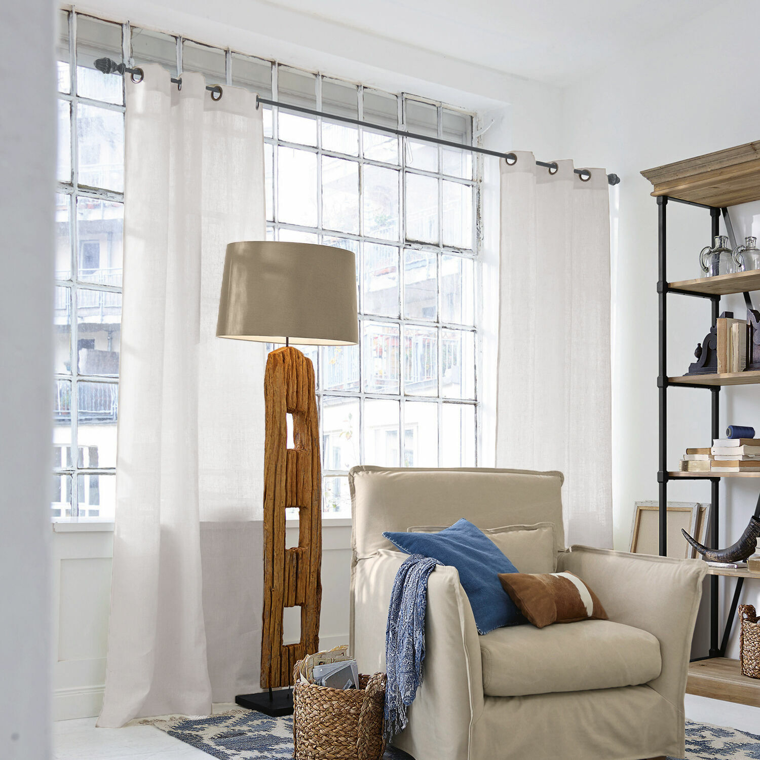 Cortina Salinas Lámpara de pie con base de madera y pantalla beige en sala luminosa con sillón y estantería