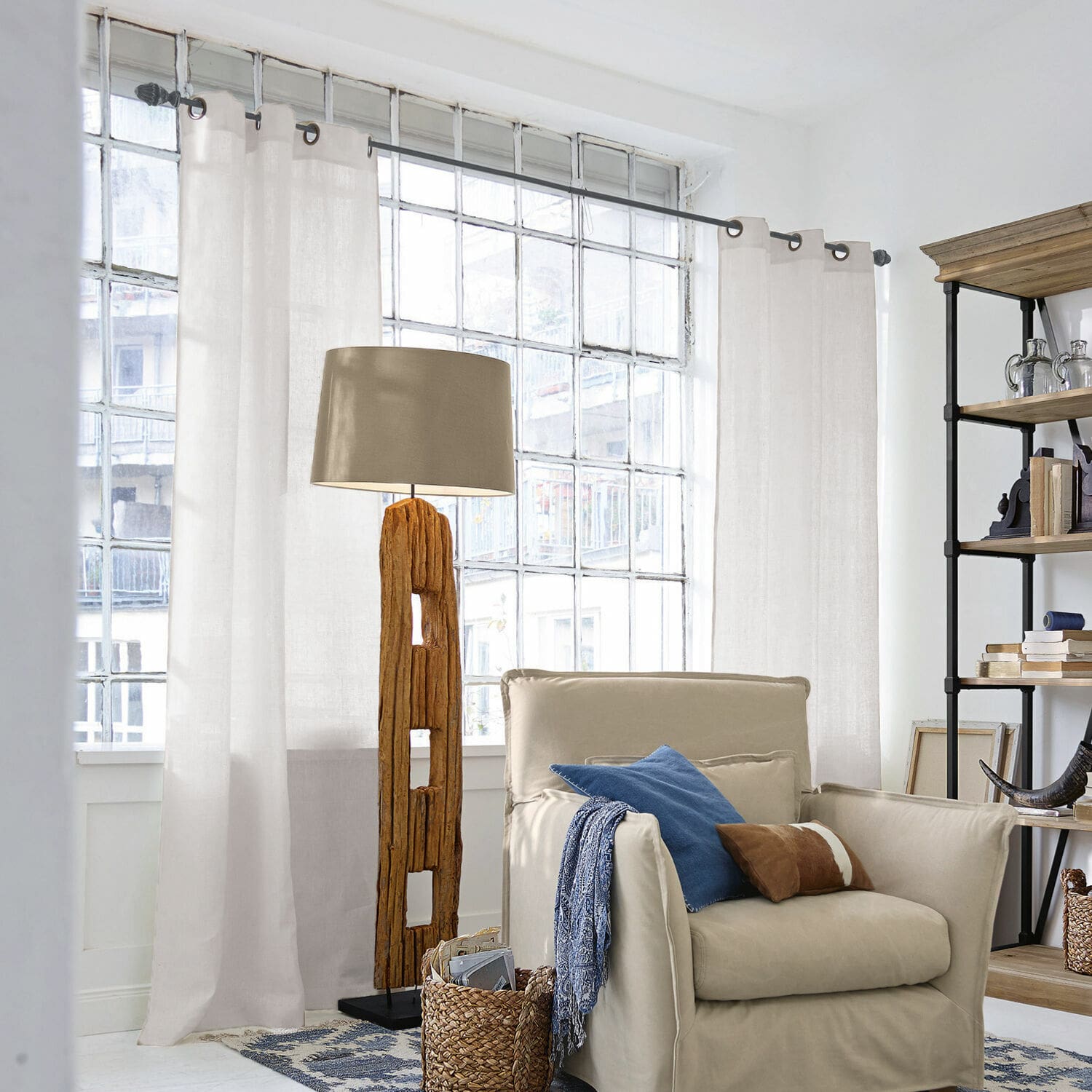 Cortina Salinas Lámpara de pie con base de madera y pantalla beige en sala luminosa con sillón y estantería