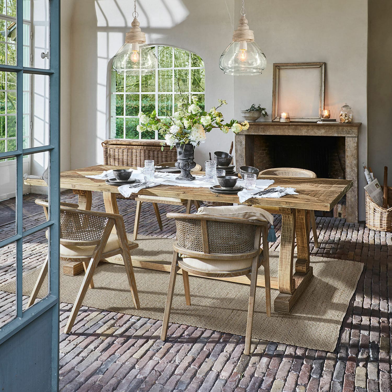 Mesa Campbelltown Comedor con mesa de madera y sillas de mimbre sobre suelo de ladrillo con decoración floral
