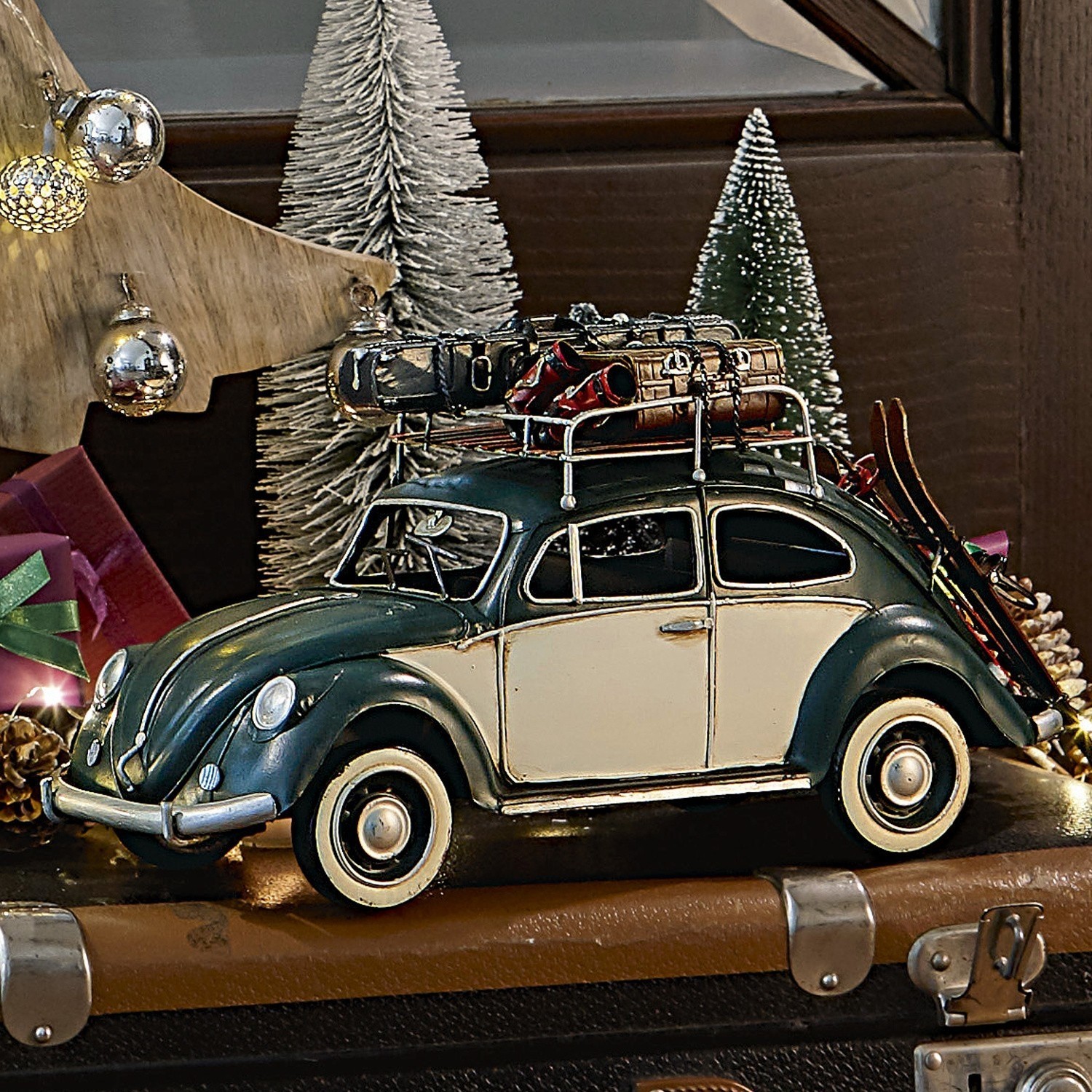 Coche decorativo Dawlish Modelo de coche verde crema con portaequipajes metálico y esquís sobre fondo de decoración navideña