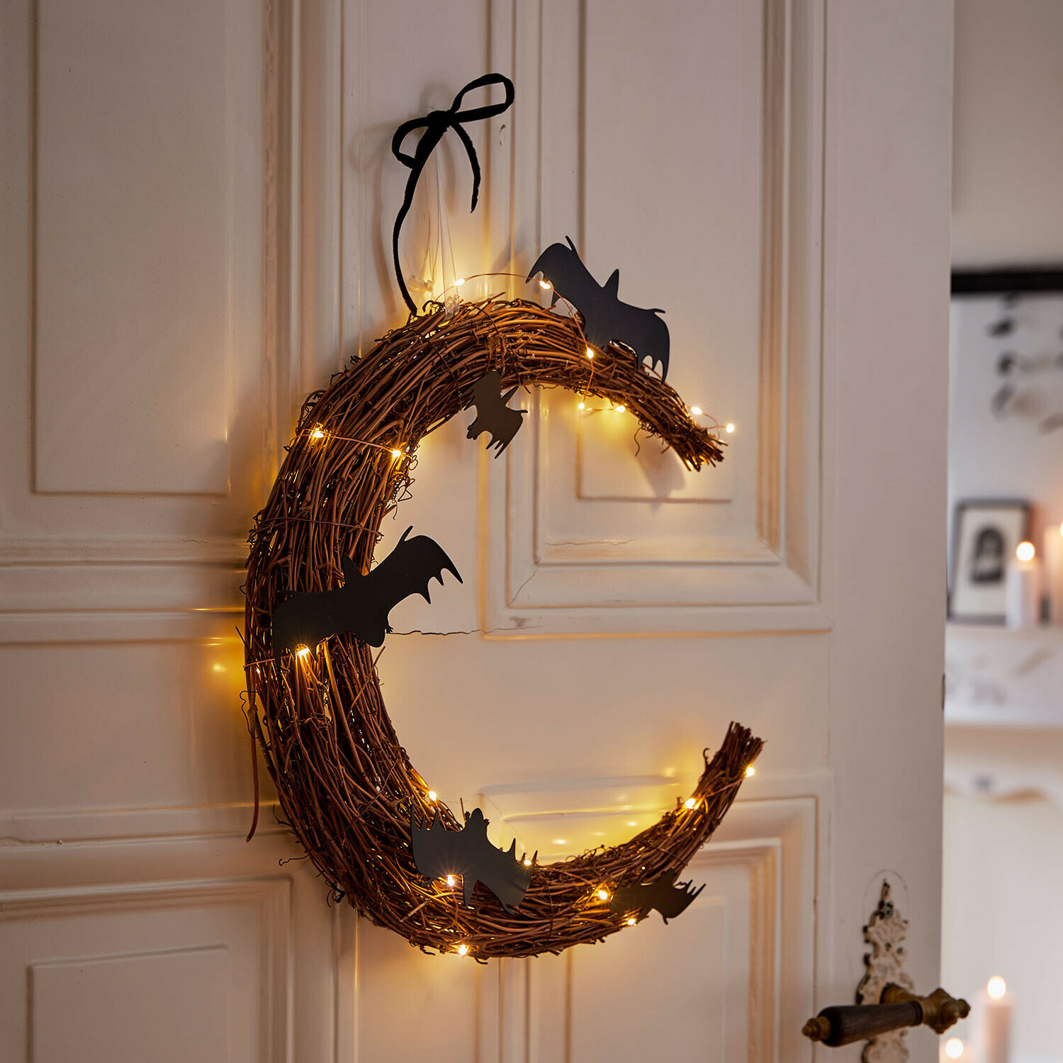 Corona LED Brynnach Corona decorativa de ramas con murciélagos negros y luces cálidas colgada en la puerta