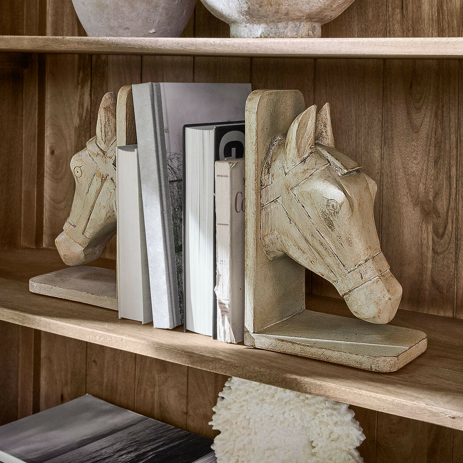 Set de 2 sujetalibros Caravena Par de sujetalibros de madera beige con forma de cabeza de caballo en estantería con libros