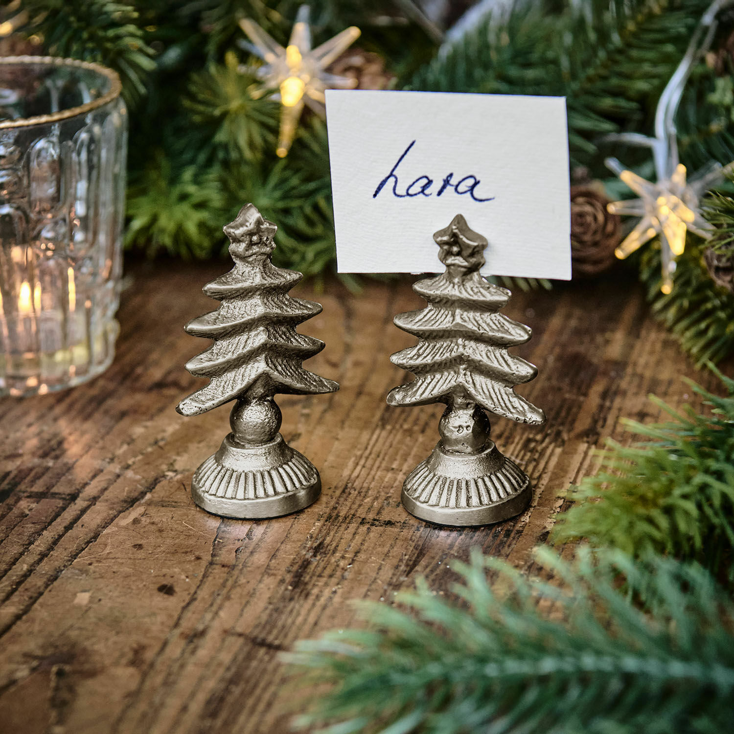 Set de 2 tarjeteros Leovian Soportes metálicos plateados para tarjetas con forma de árbol de Navidad sobre mesa de madera con decoración navideña