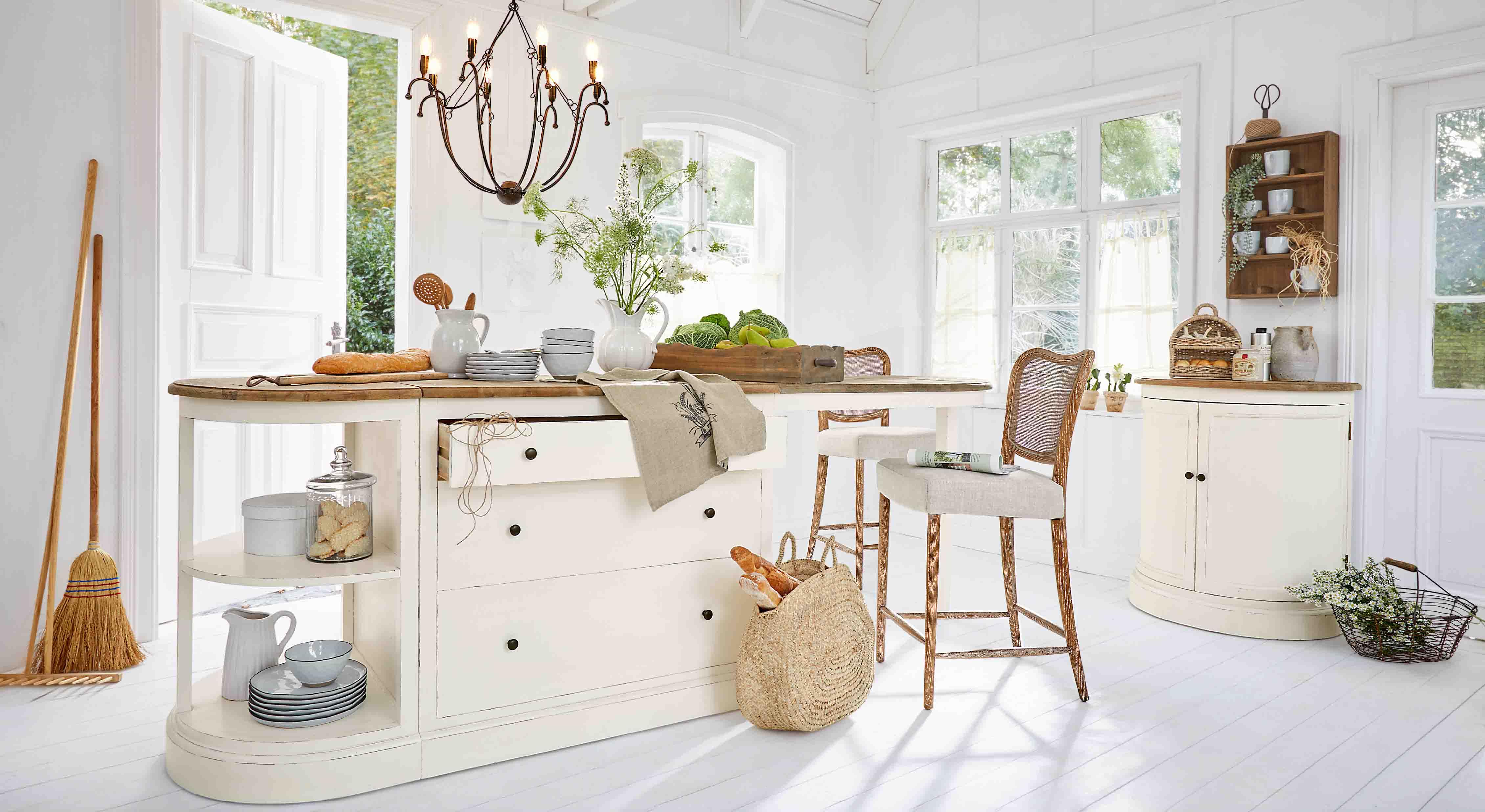 Cocina luminosa con isla blanca de madera y sillas de mimbre, decoración natural