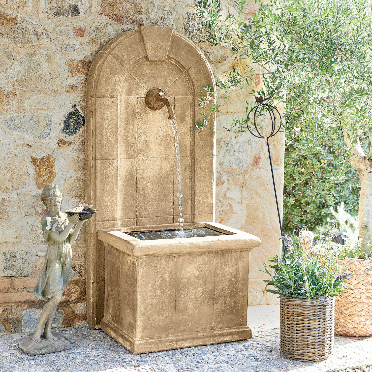 Fuente Ginette Fuente decorativa de jardín de piedra beige con agua y estatua de niña frente a muro de piedra