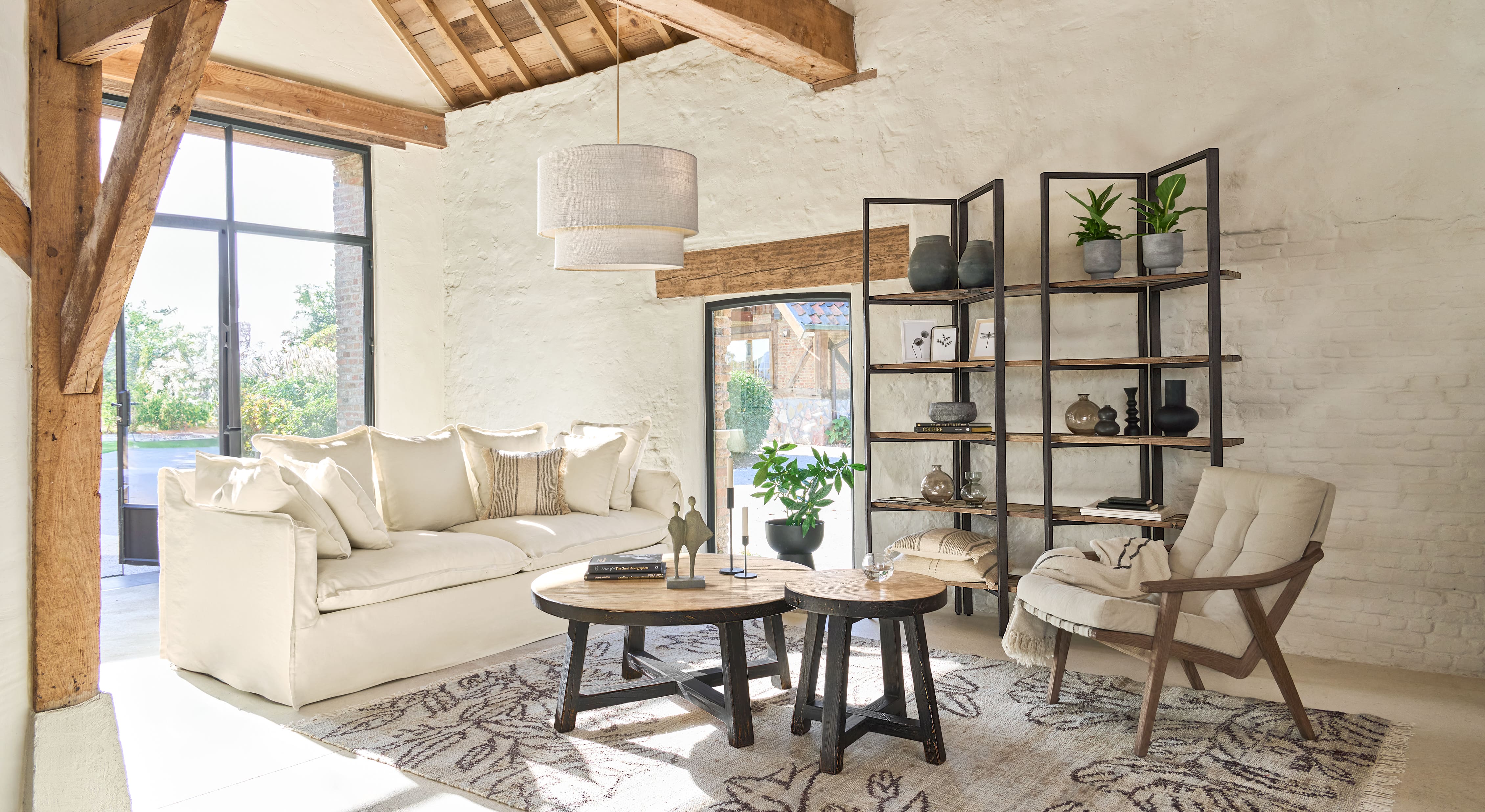 Salón acogedor con sofá blanco, mesas de madera y estantería de metal y madera, estilo natural