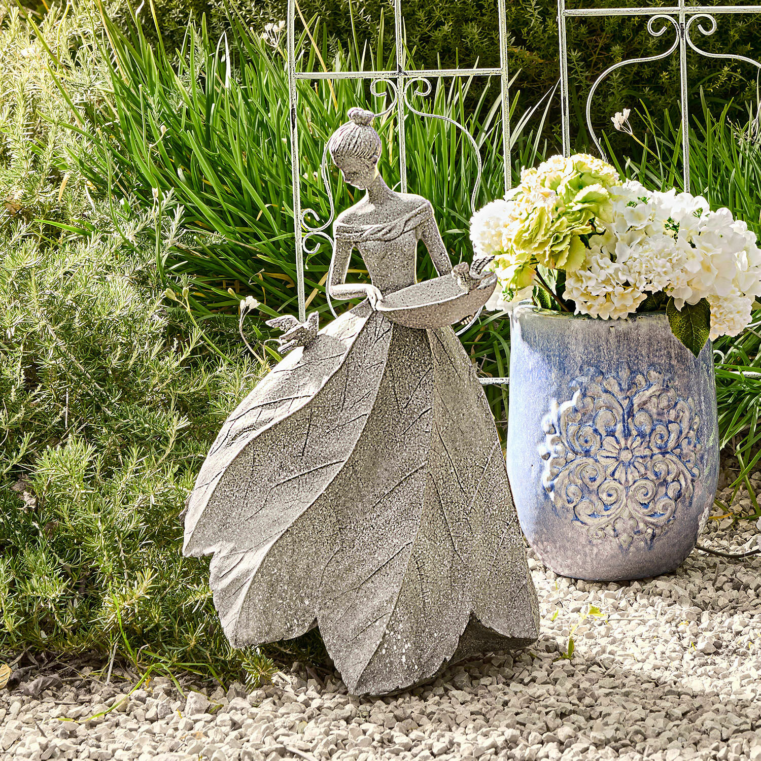 Escultura Sullon Decoración de jardín en piedra gris con figura femenina y vestido de hojas sobre grava