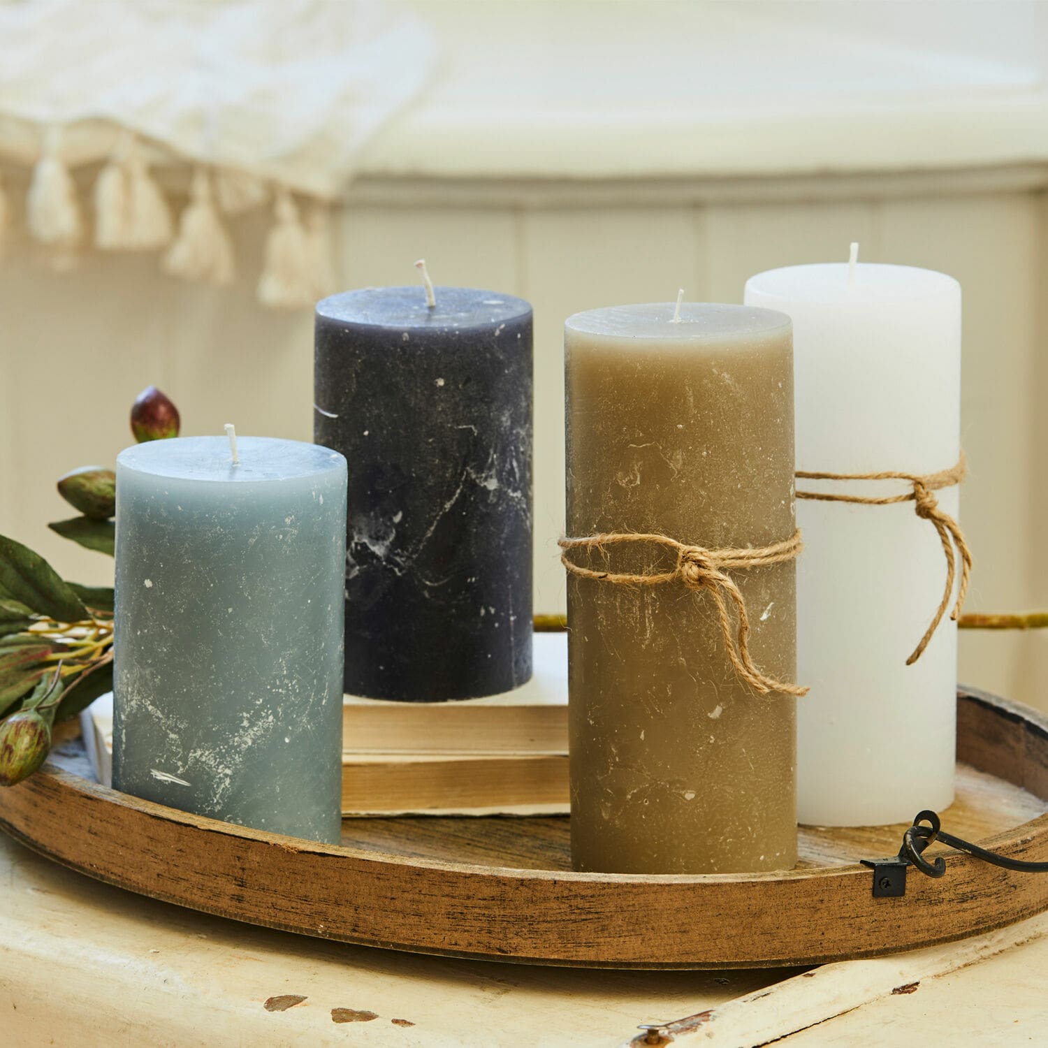 Conjunto de cuatro velas en azul, negro, marrón y blanco sobre una bandeja decorativa de madera