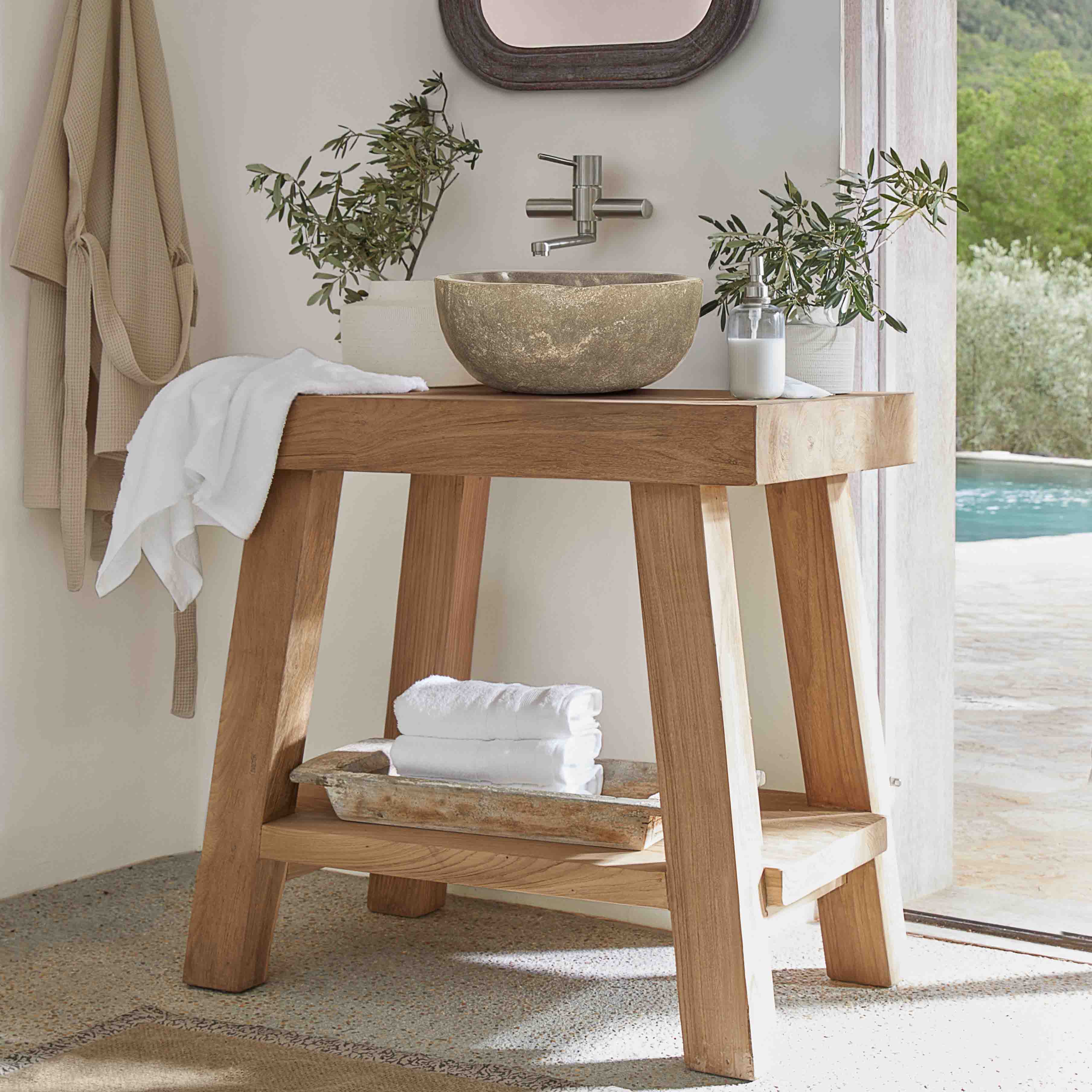 Consola de baño de madera con lavabo de piedra y toallas blancas en interior luminoso