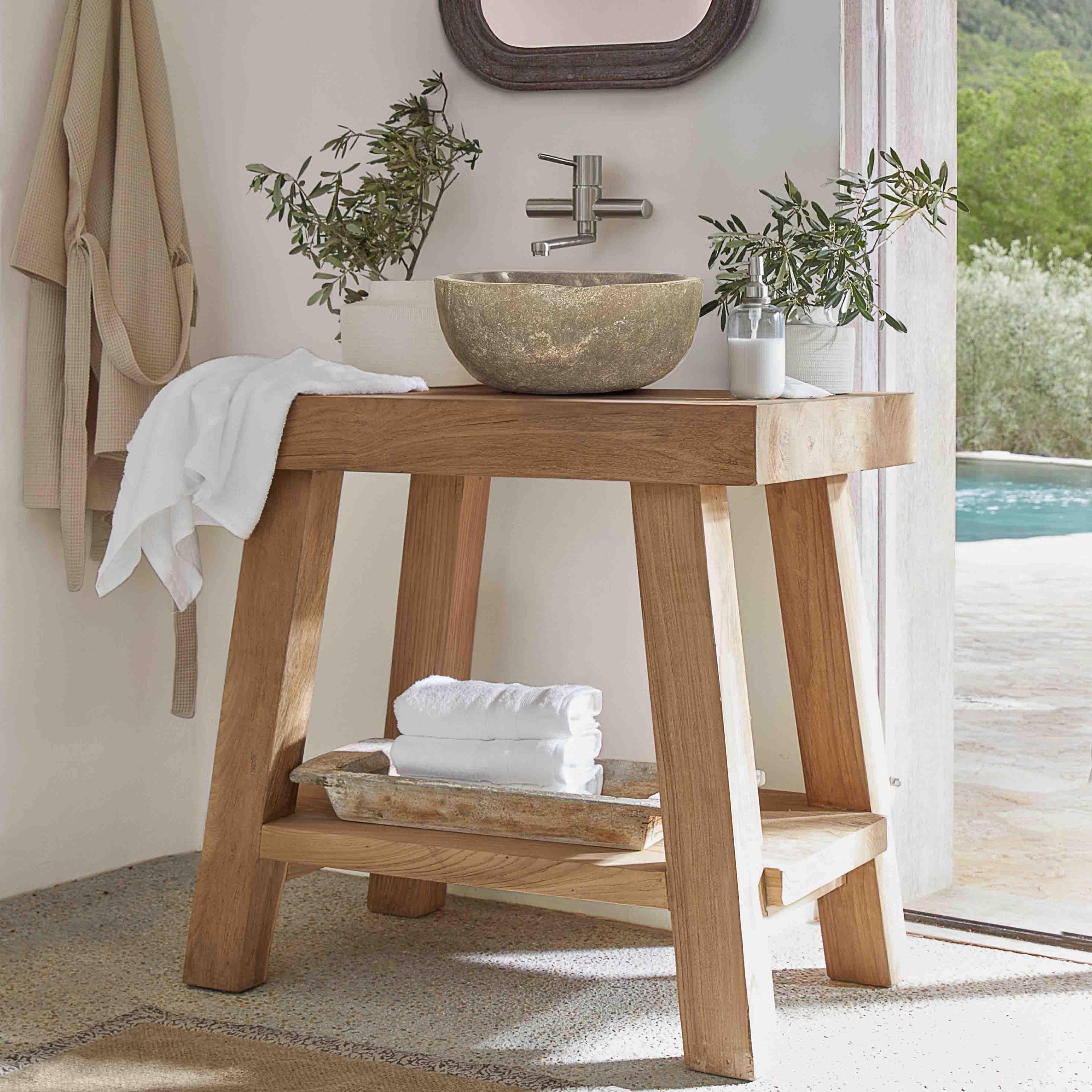 Consola de baño de madera con lavabo de piedra y toallas blancas en interior luminoso