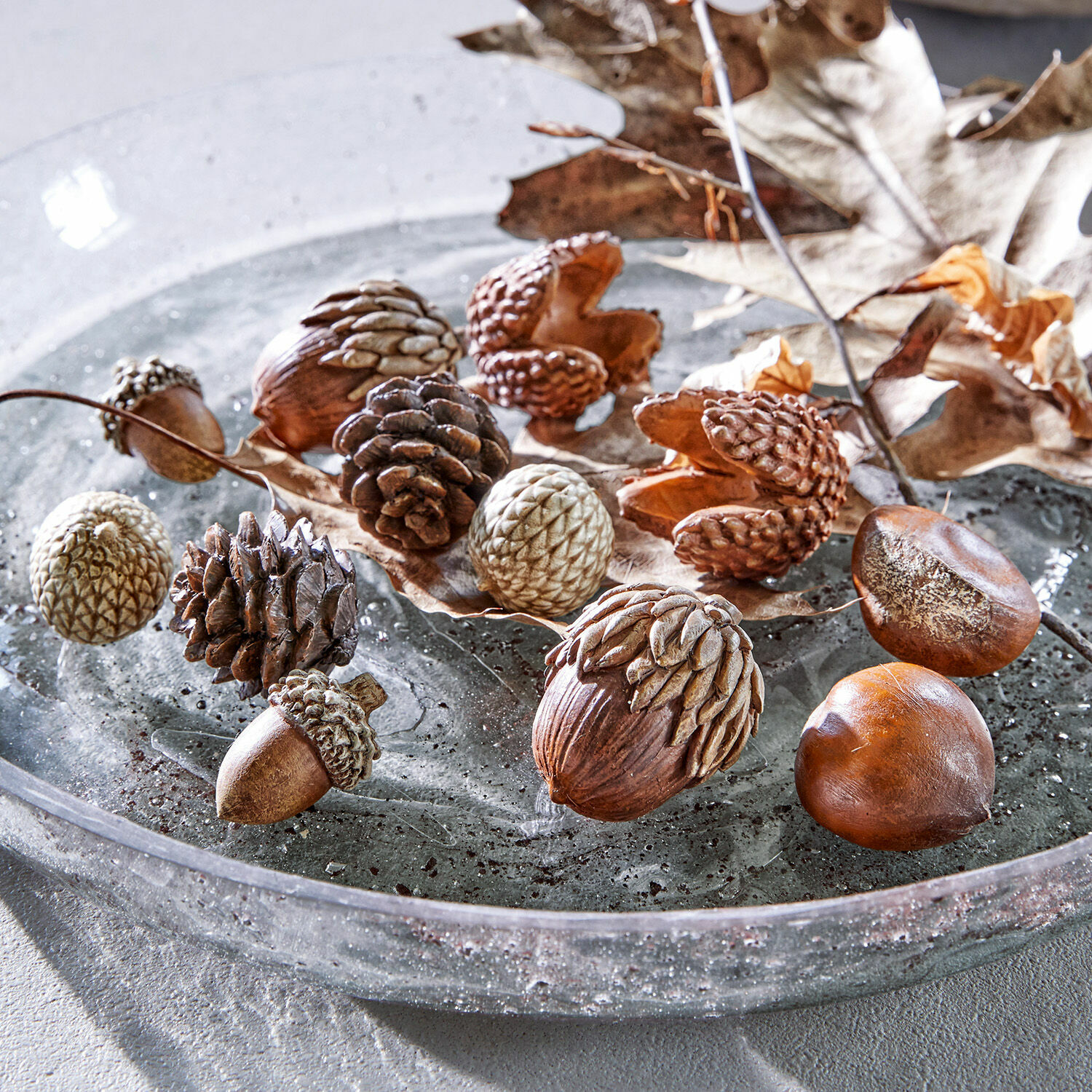 Set de 12 objetos decorativos de otoño Vibius Nueces decorativas y piñas en tonos marrones naturales sobre plato de vidrio para decoración otoñal